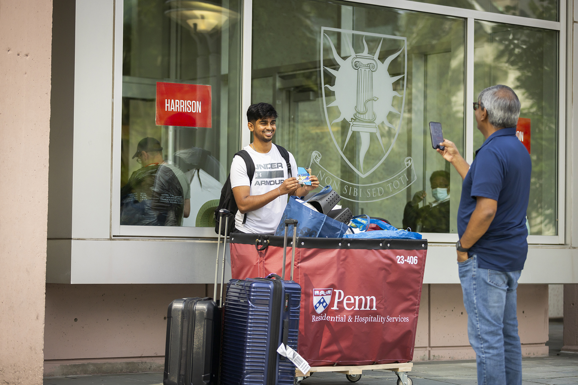 A parent takes a photo of a student moving into a dorm.