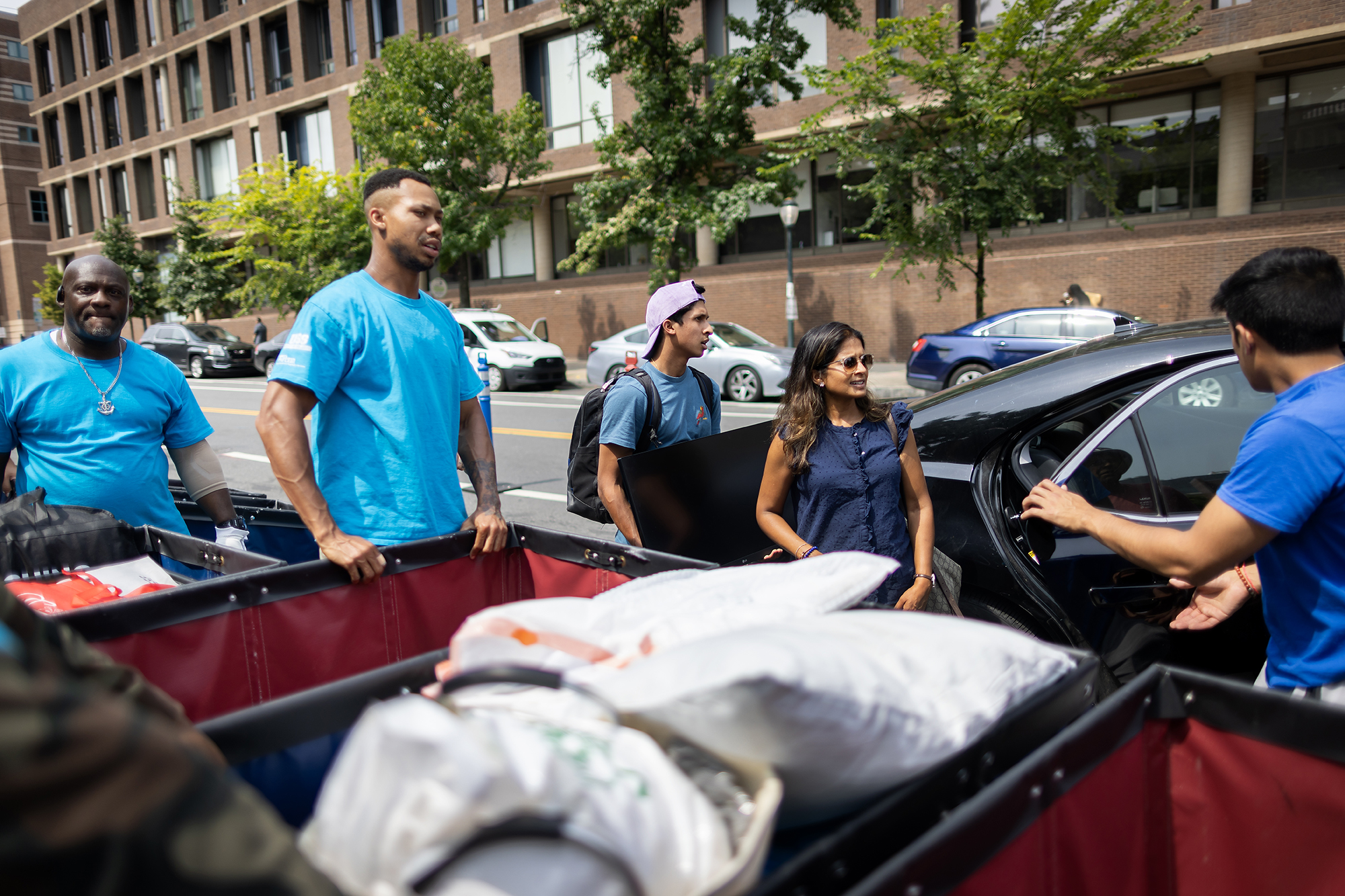 Move-In helpers greet a family at their car with Move-In bins.