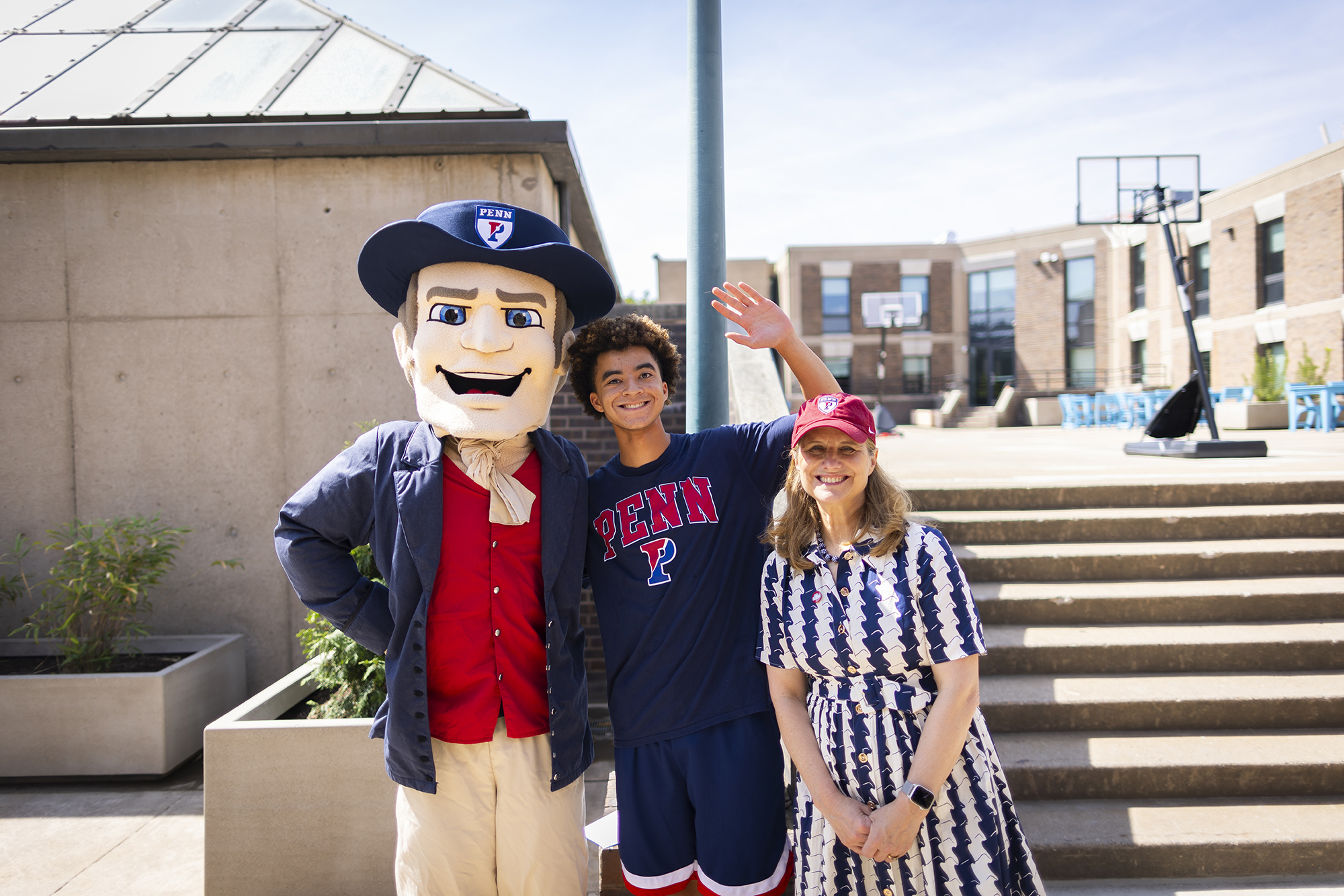 Penn President Liz Magill and the Penn Quaker mascot with a new student who is waving.