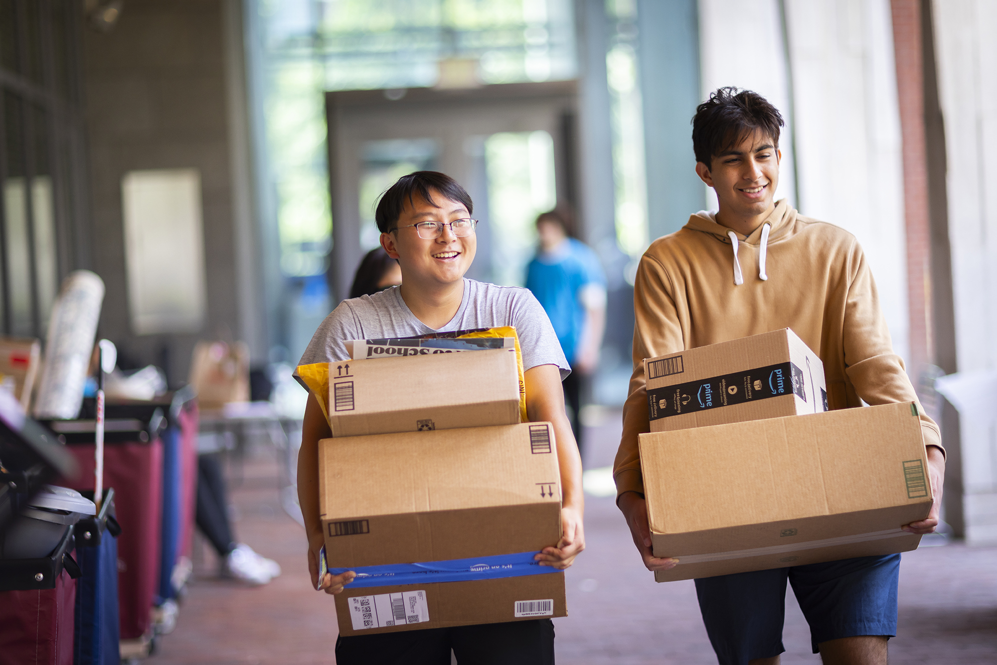 Two students carrying several moving boxes on Move-In day.