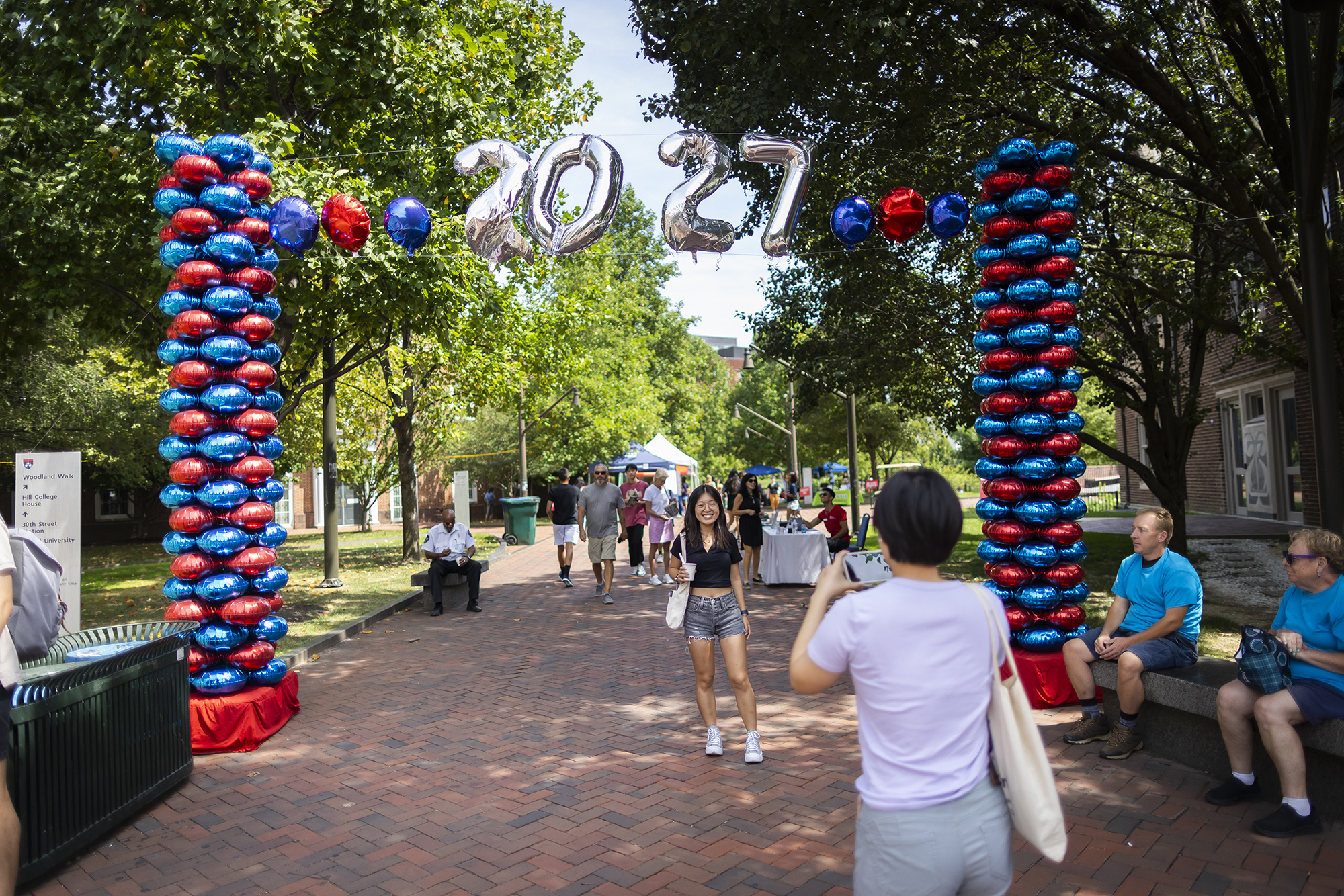 A person standing under the 2027 balloon banner on Penn’s campus on Move-In day.