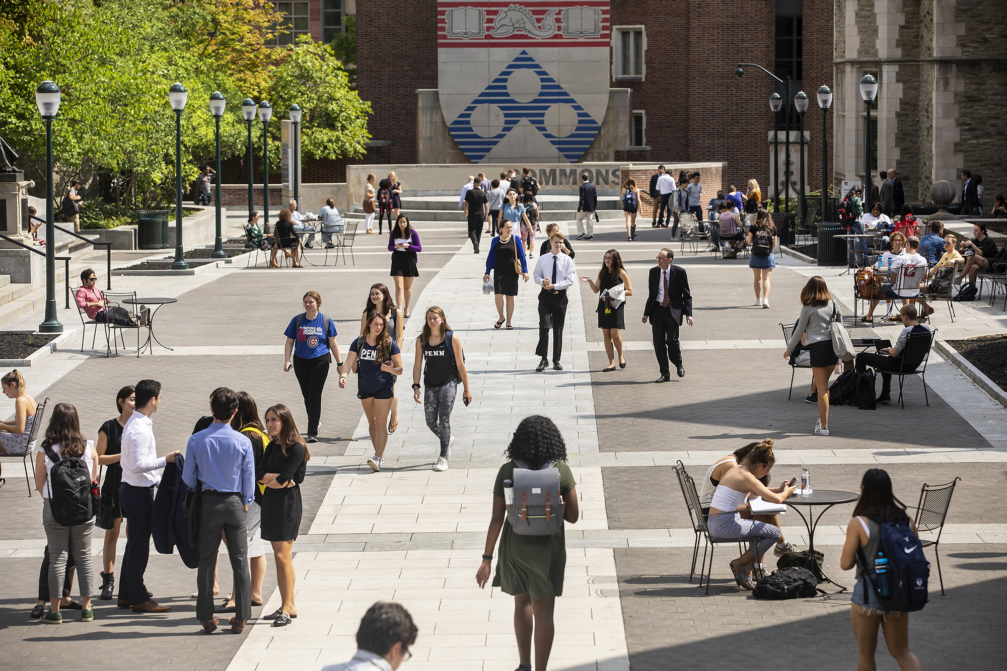 students walking in penn commons with penn shield in background