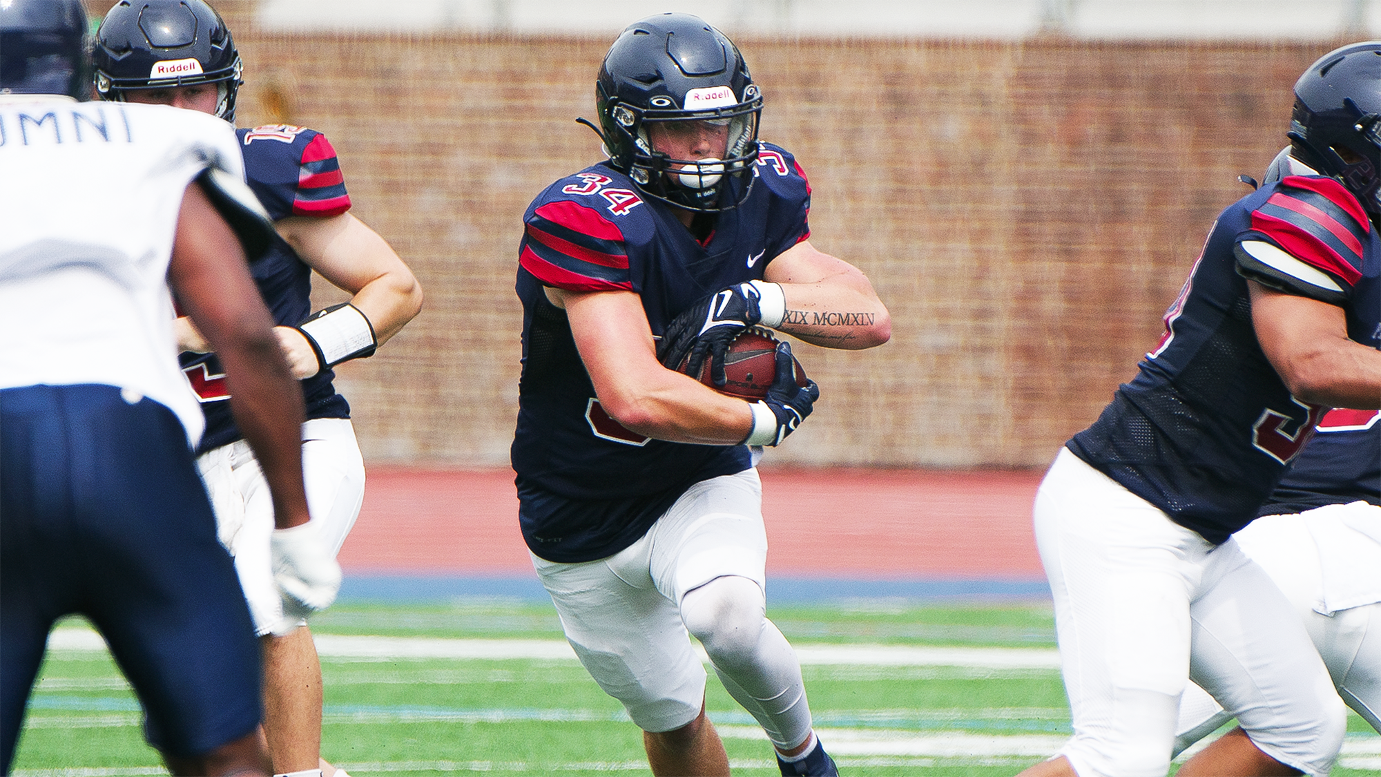 JT Goodman carries the ball through a hole created by two blockers on each side.