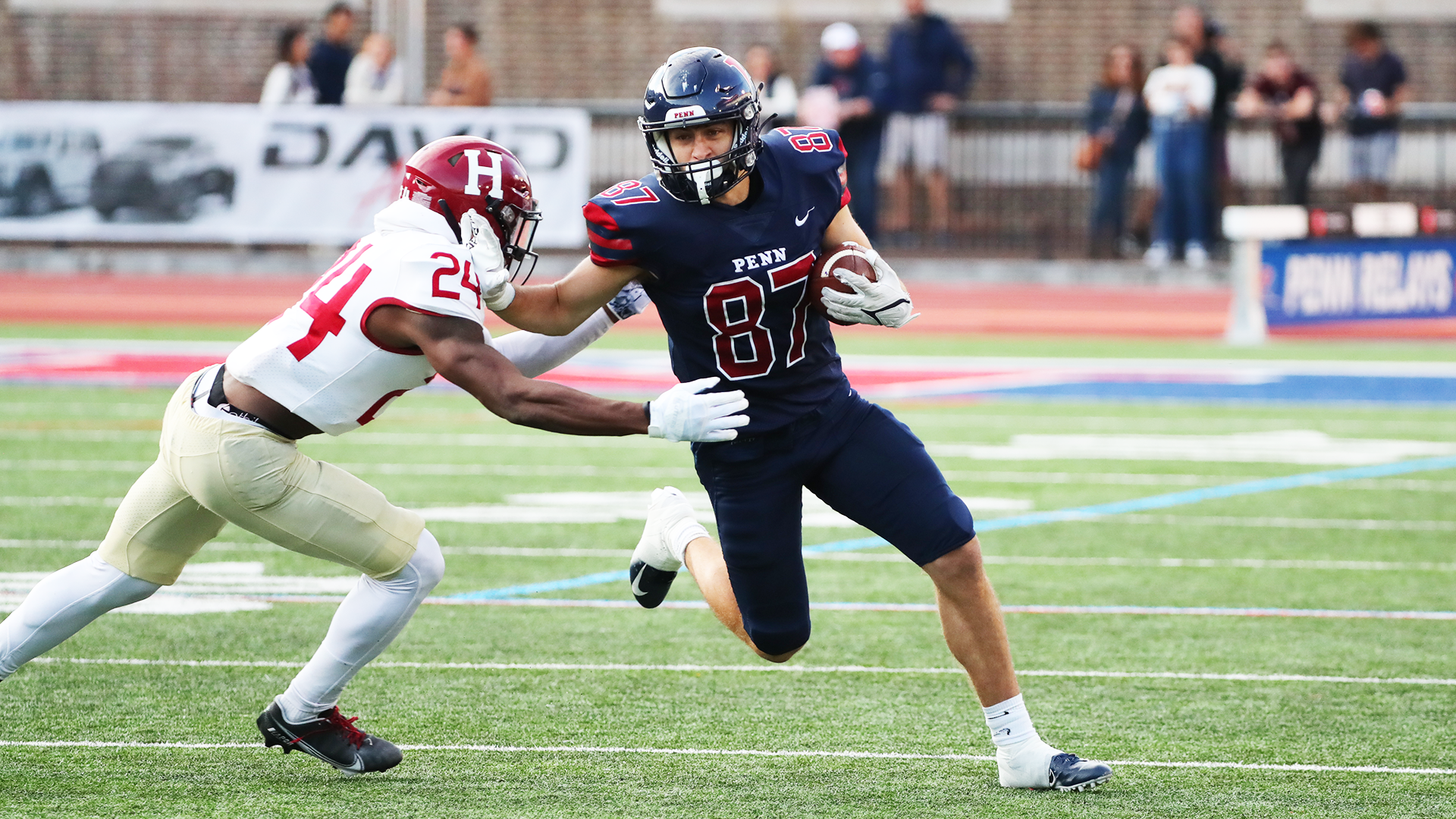 Joshua Casilli stiff arms a Harvard defender while running with the ball during a game at Franklin Field.
