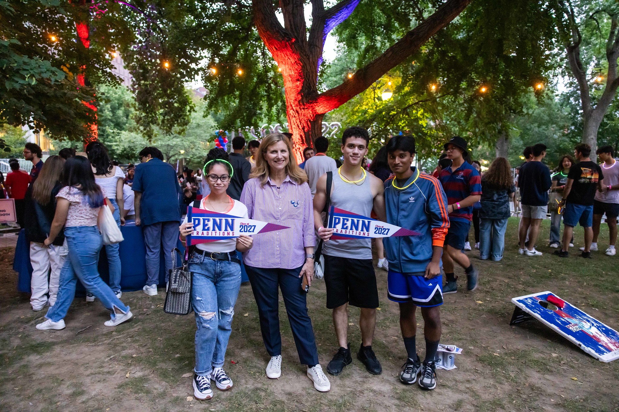 penn president liz magill with students holding pennants on college green