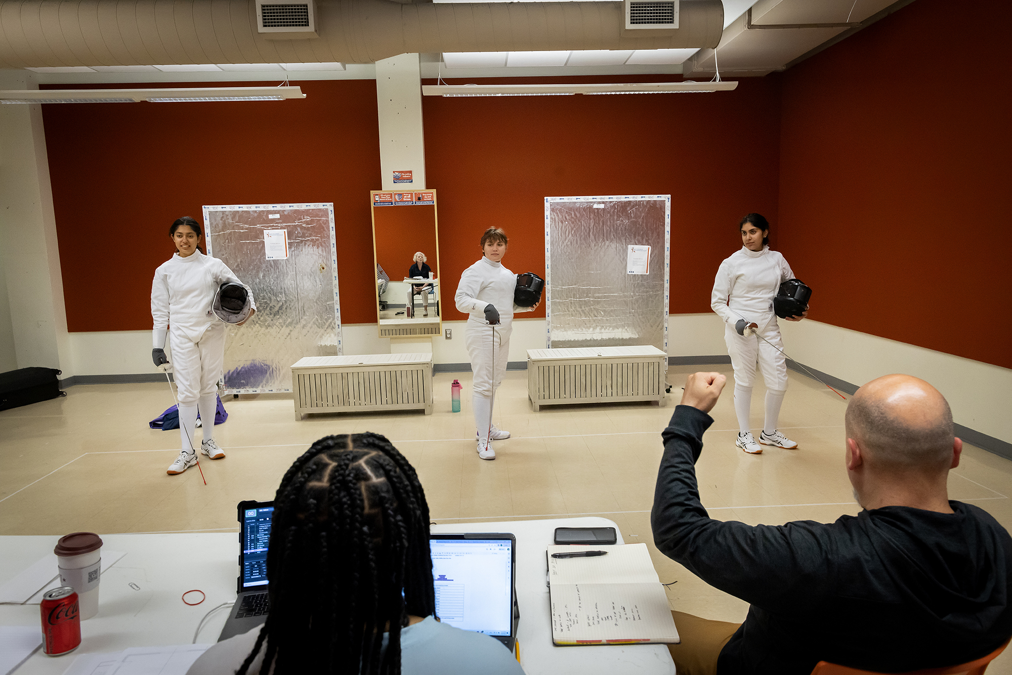Three actors in fencing gear are directed during play rehearsal.