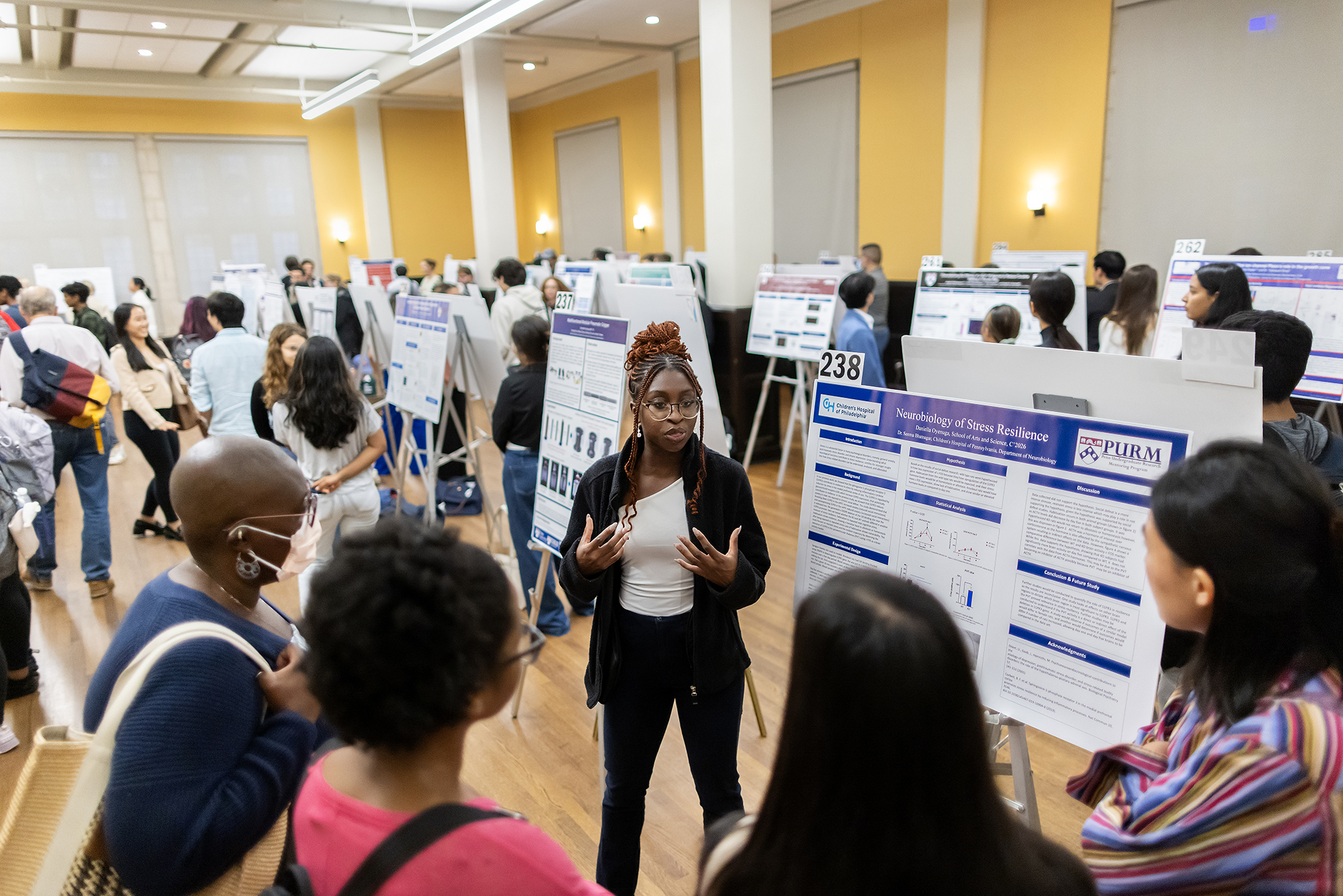 A student discusses their poster with others at the CURF poster expo.