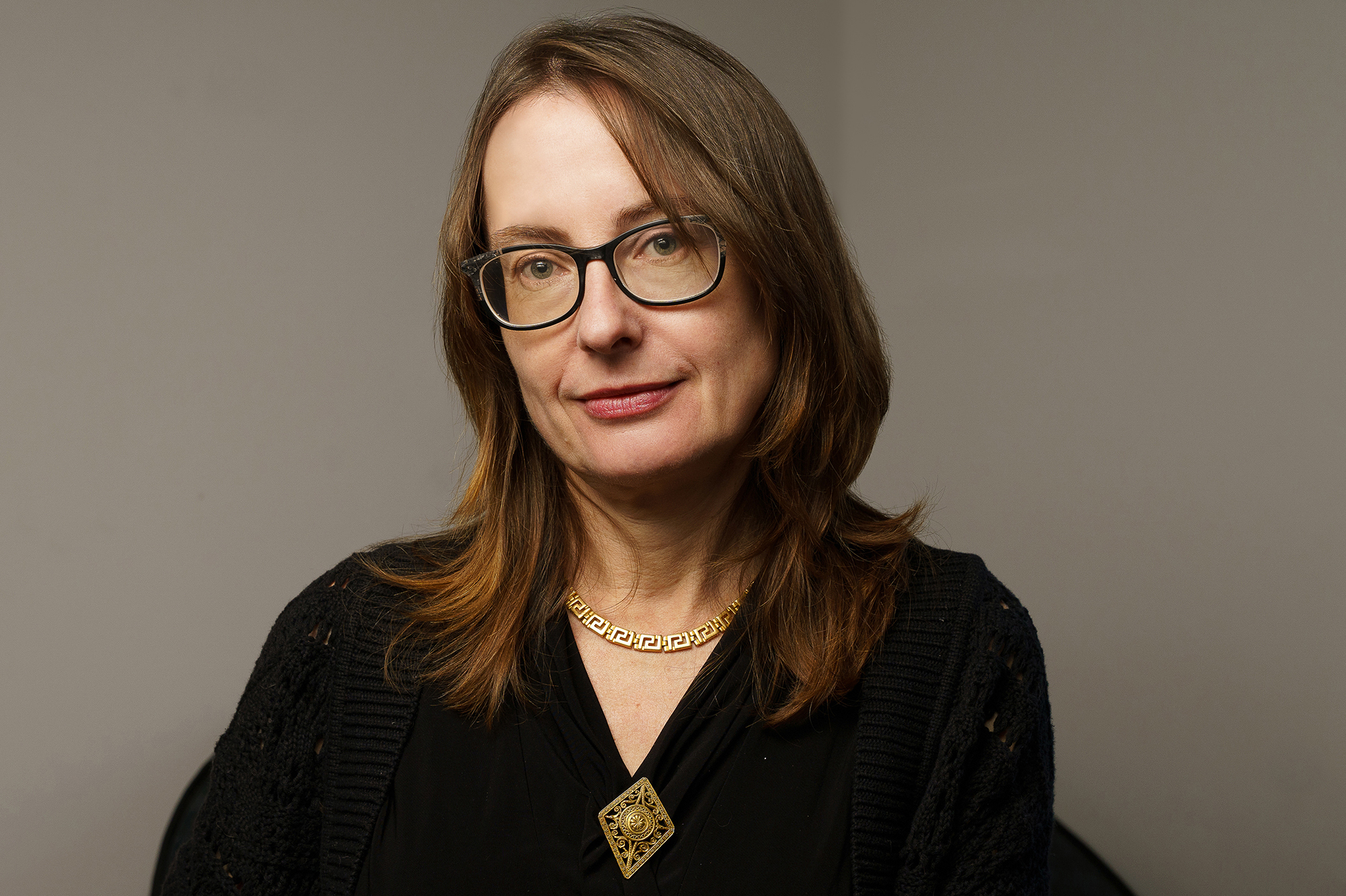 Emily Wilson, wearing glasses and a Greek necklace, smiles.