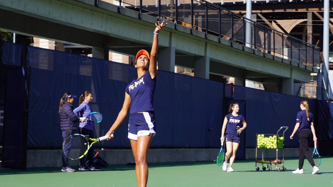 Esha Velaga throws the ball in the air and prepares to service during a game.