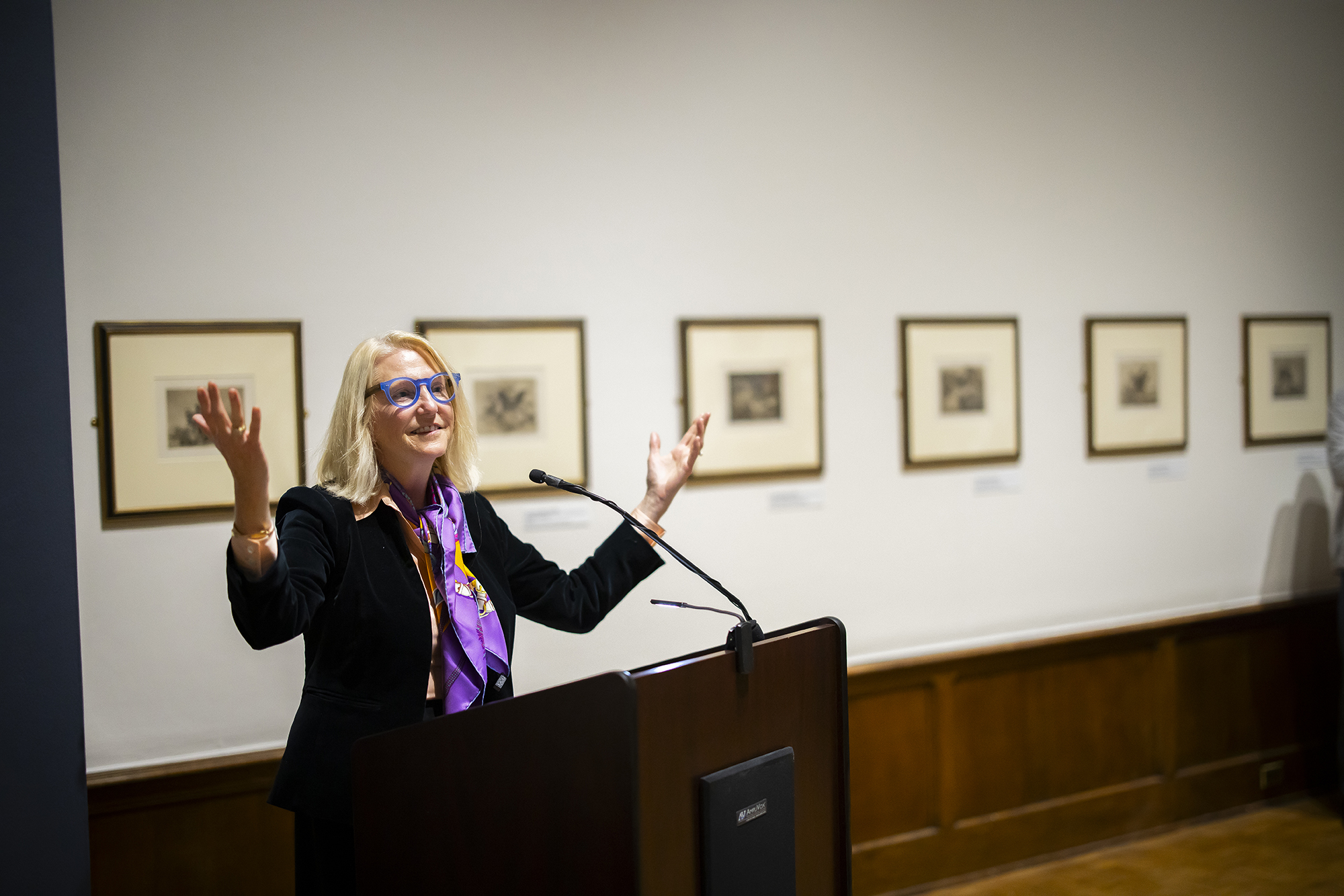 Lynn Marsden-Atlass speaking at podium with arms gesturing upwards