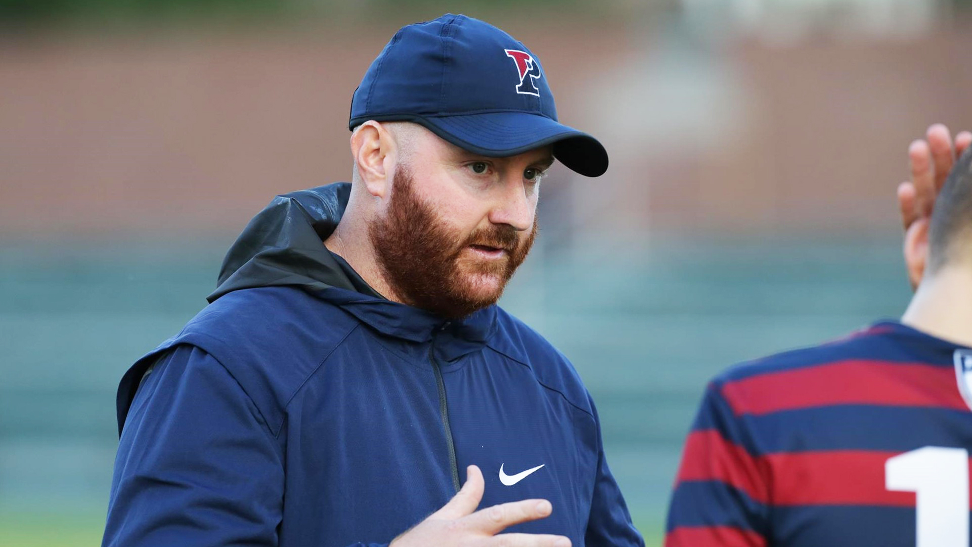 Brian Gill speaks with a player on the sidelines during a game.