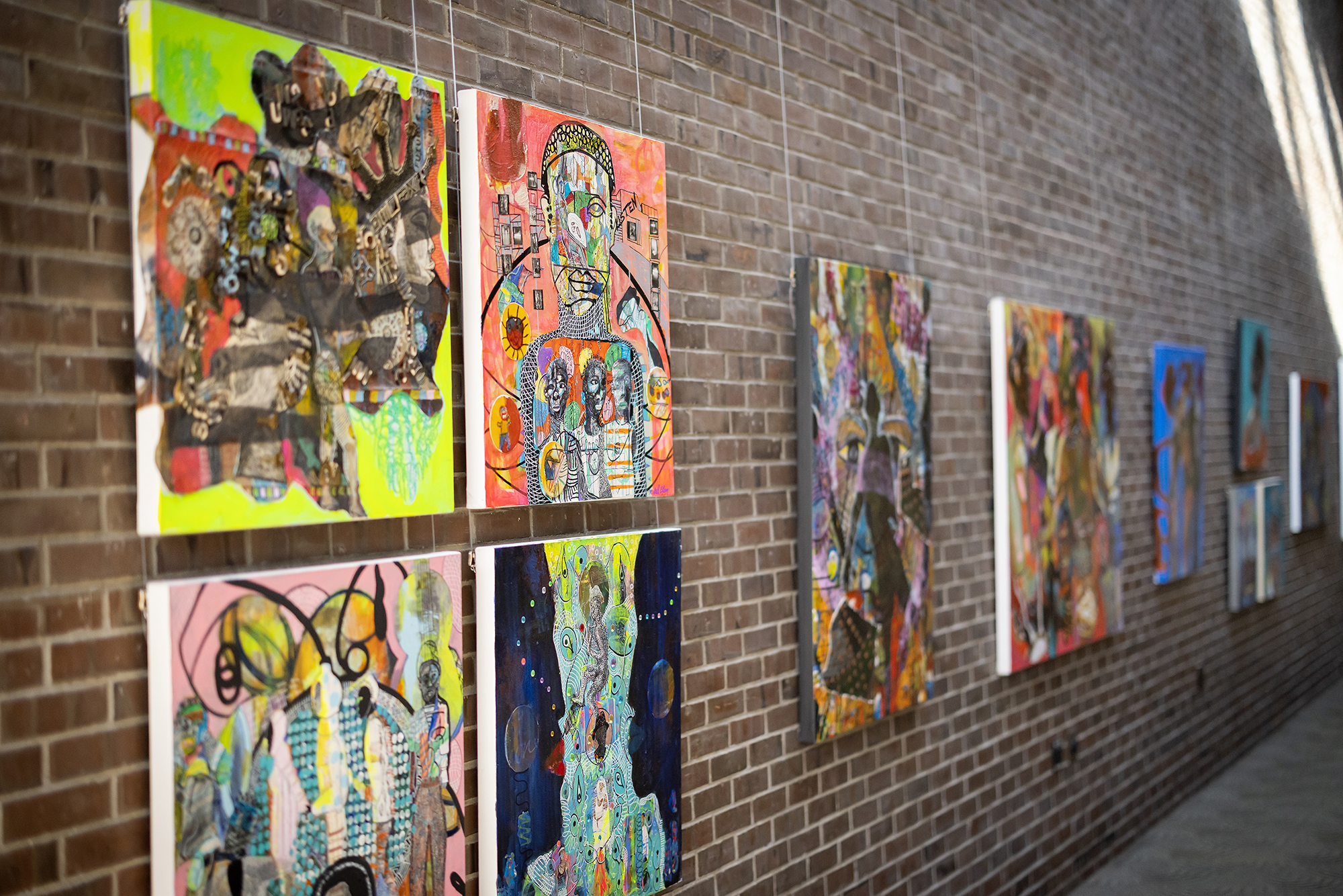 A series of artworks hung on a brick wall. 