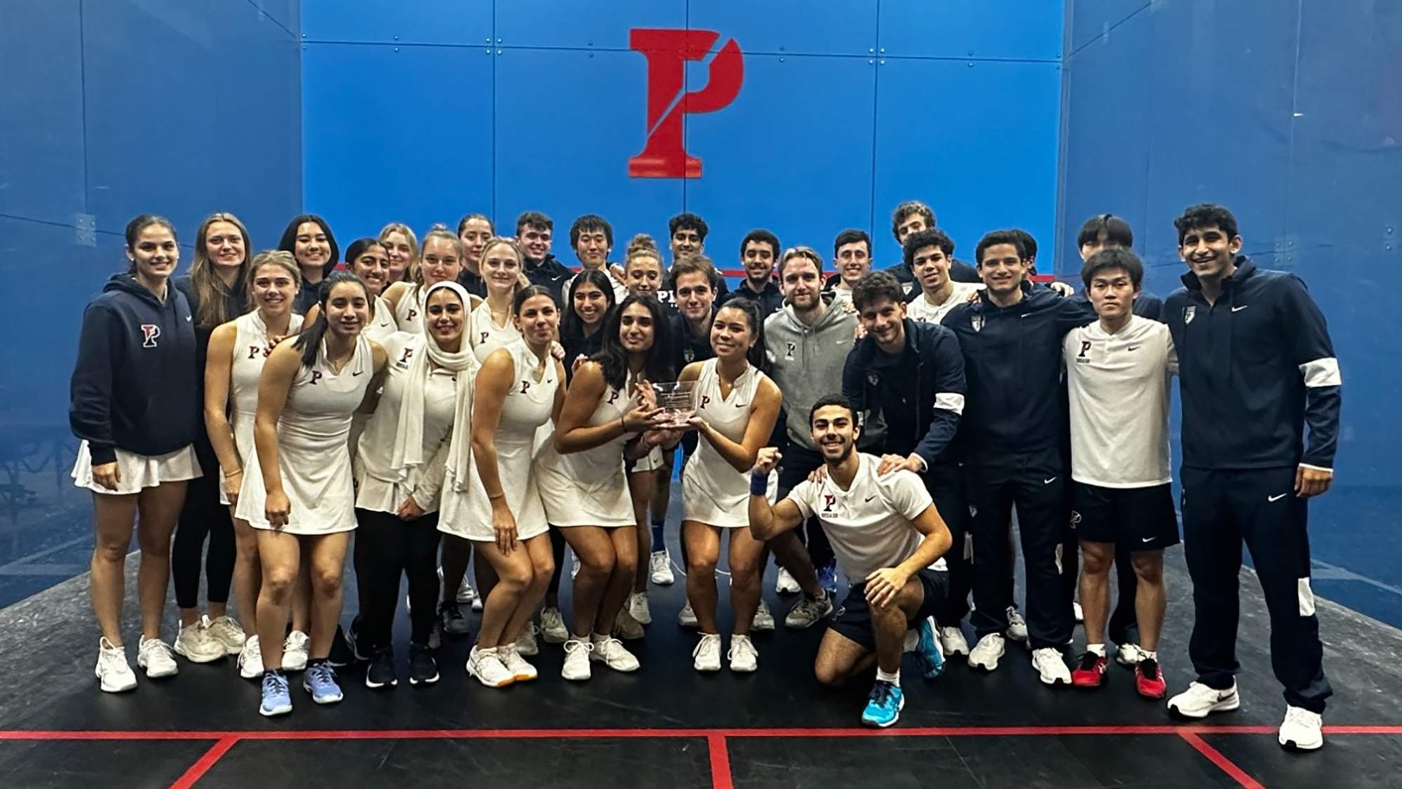 Members of the men's and women's squash teams pose on the court at the Penn Squash Center.