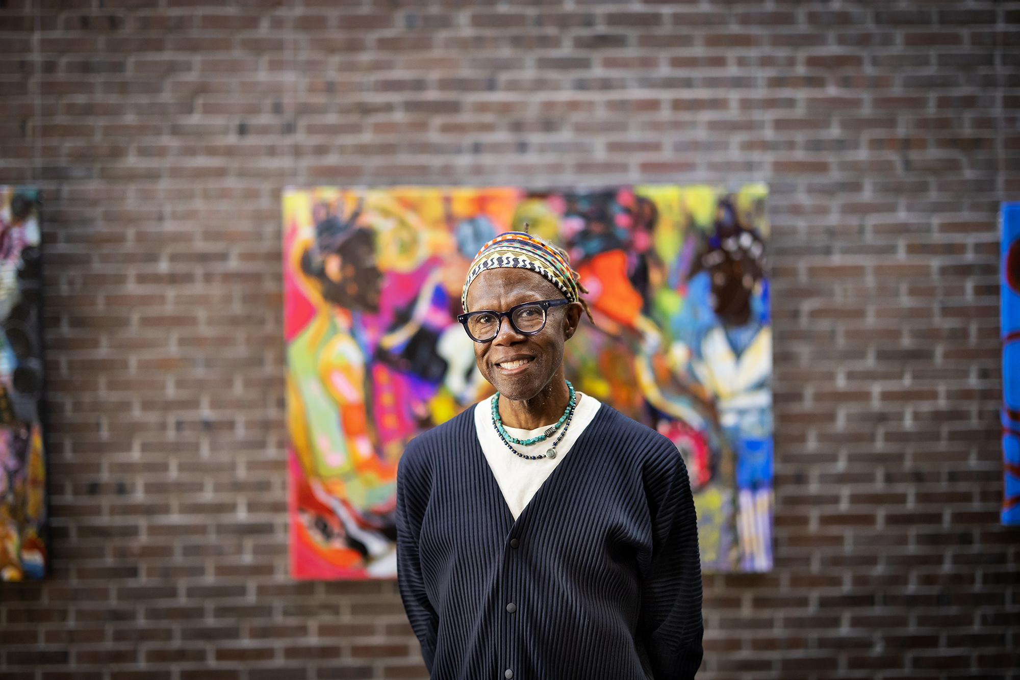 Mikel Elam poses in front of artwork.