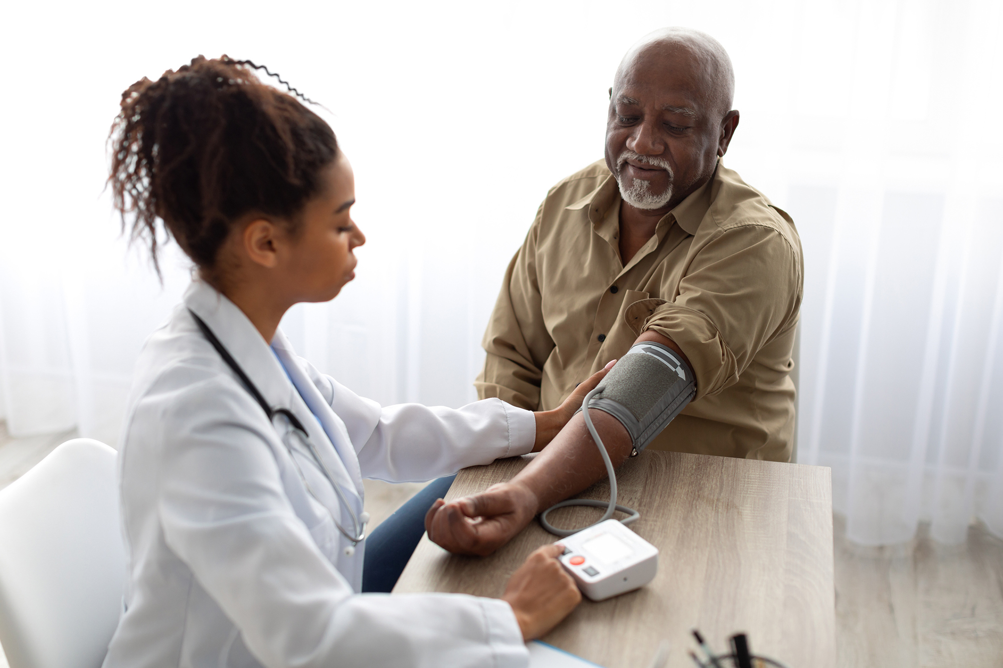A medical professional takes the blood pressure of a mature patient.