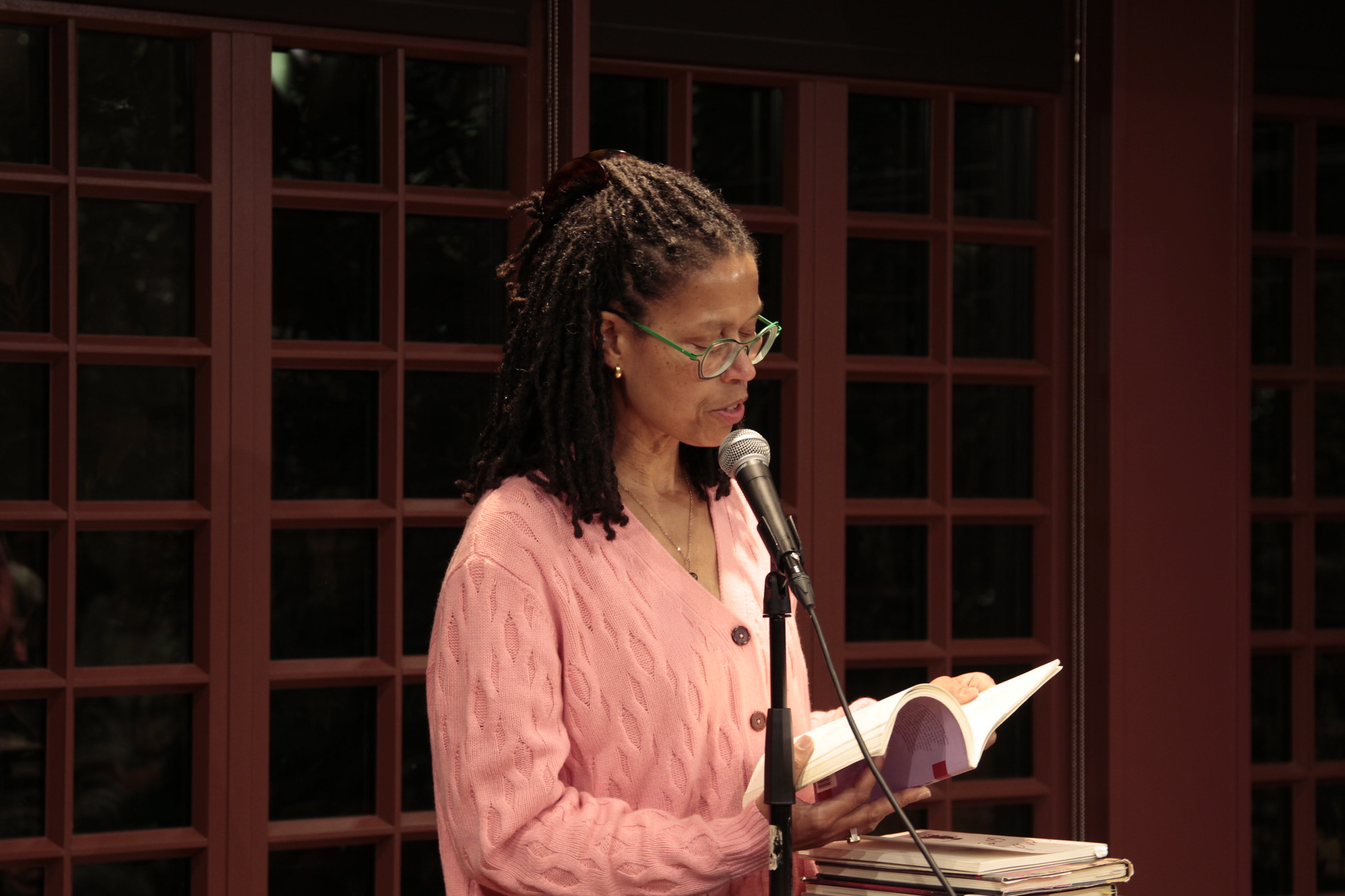 Evie Shockley reading a book at a microphone standing at a podium