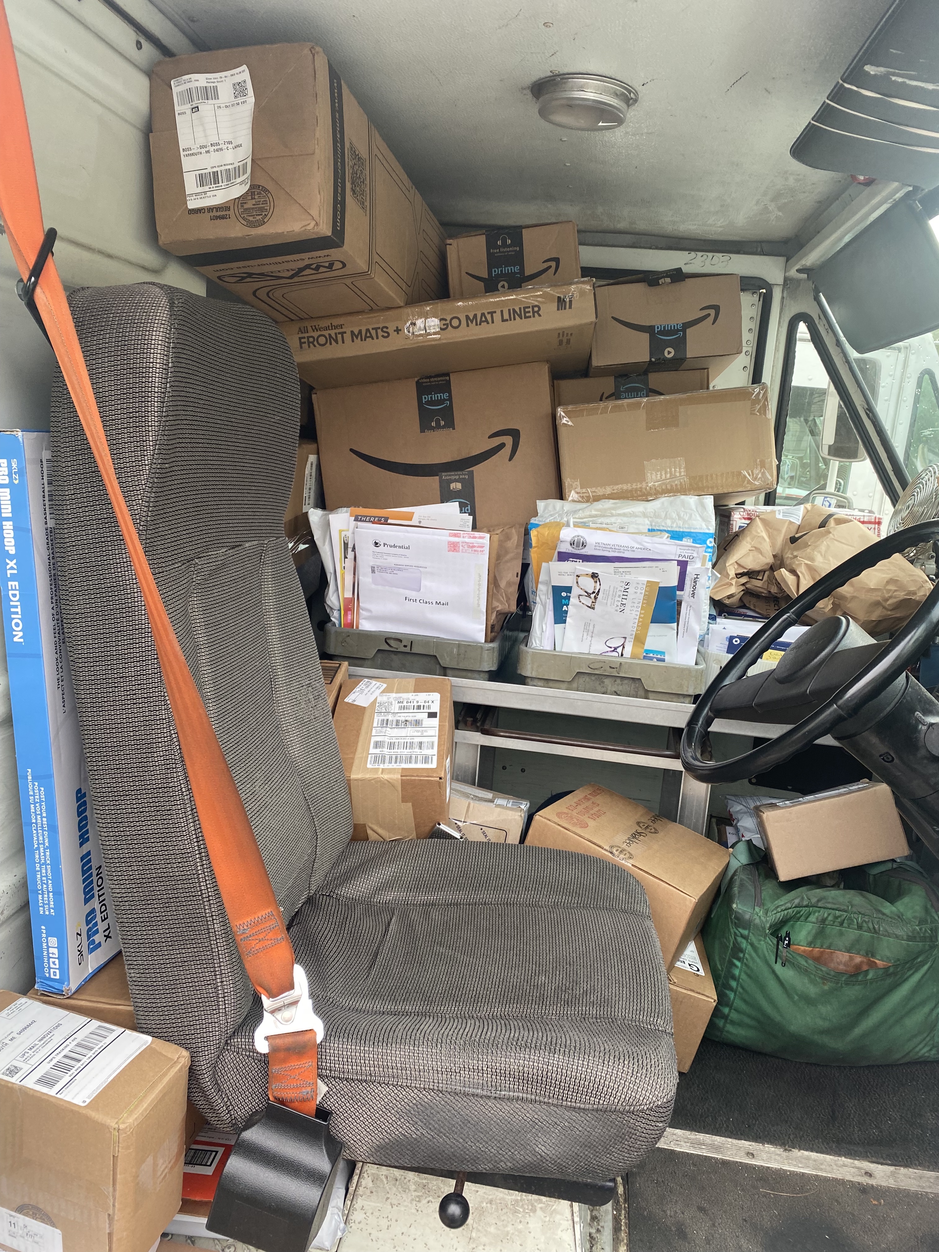 A view of the inside of a delivery truck, with stacks of boxes and letters. 
