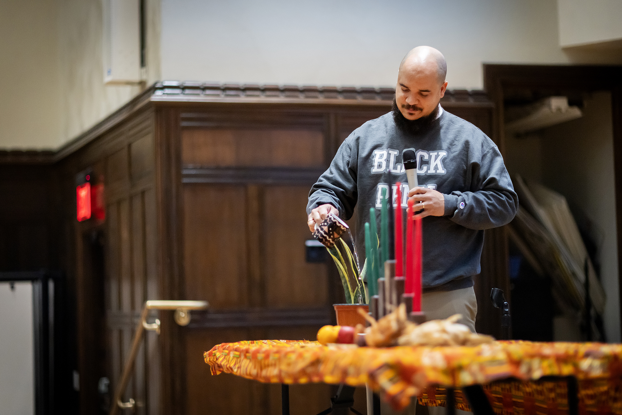 Chaz Howard pours out libations into a plant. Red and green candles mark the days of Kwanzaa. 