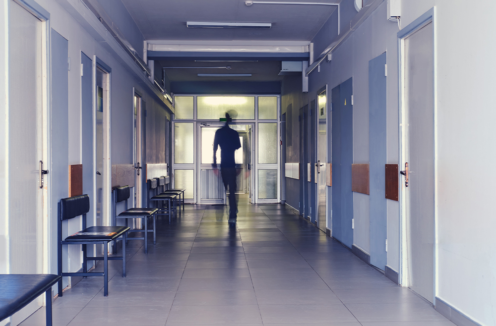 A person leaving the hospital at the end of a long corridor.