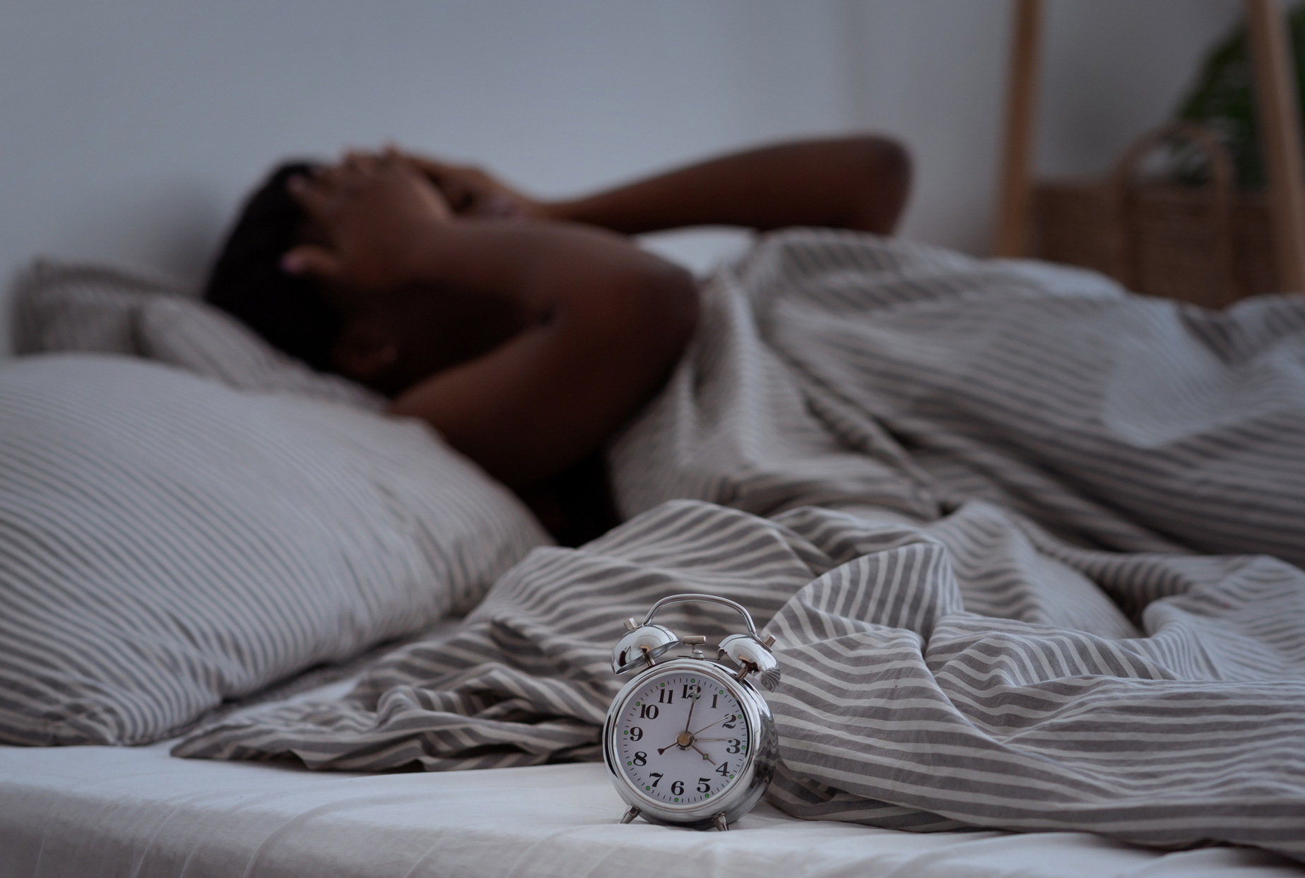 Person awake in bed with alarm clock reading 4 a.m.