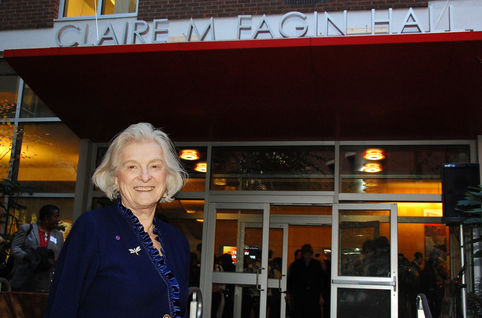 Claire Fagin stands in front of Claire M. Fagin Hall on Penn campus.