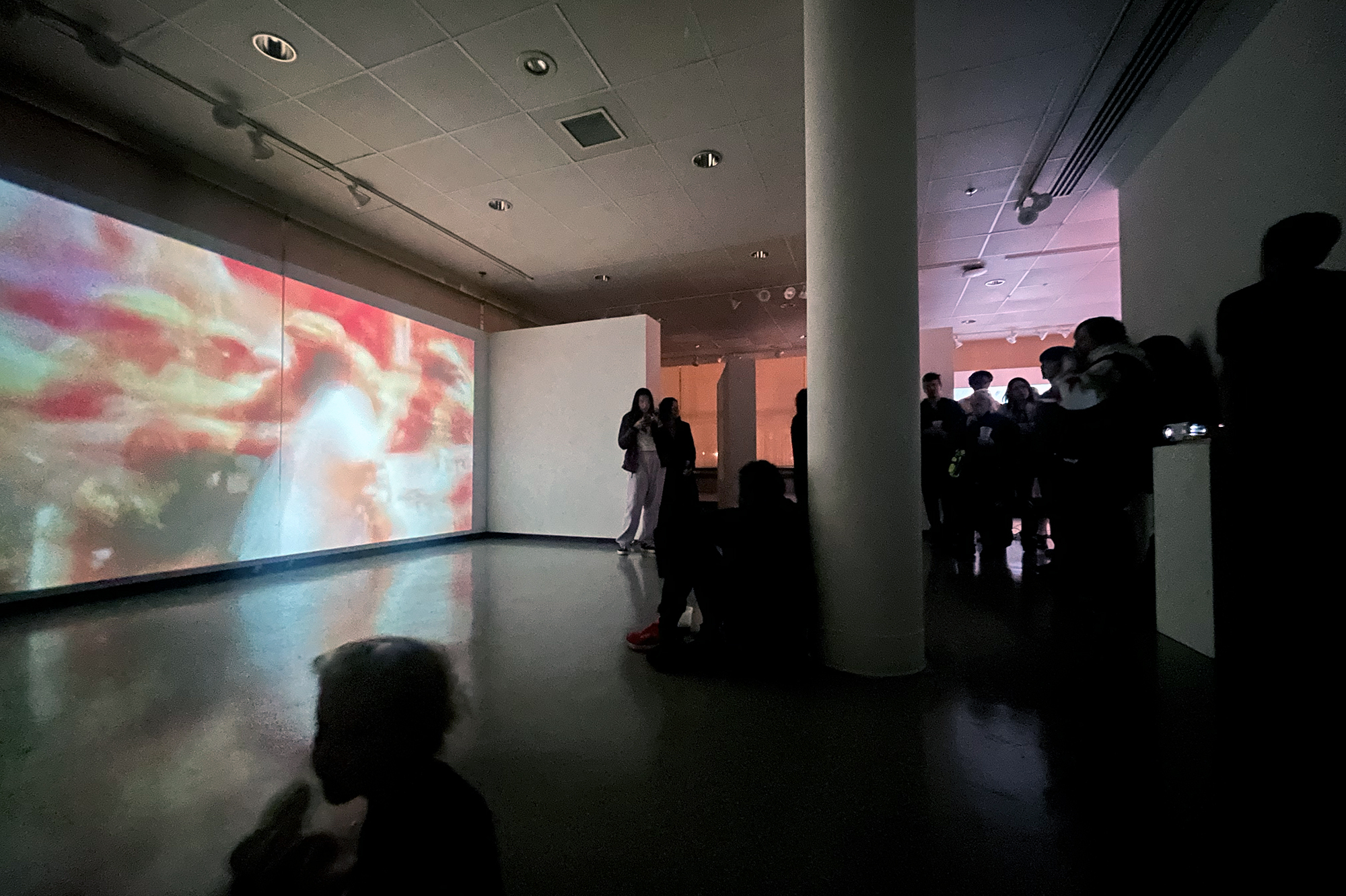 People watching a film installation in a gallery.
