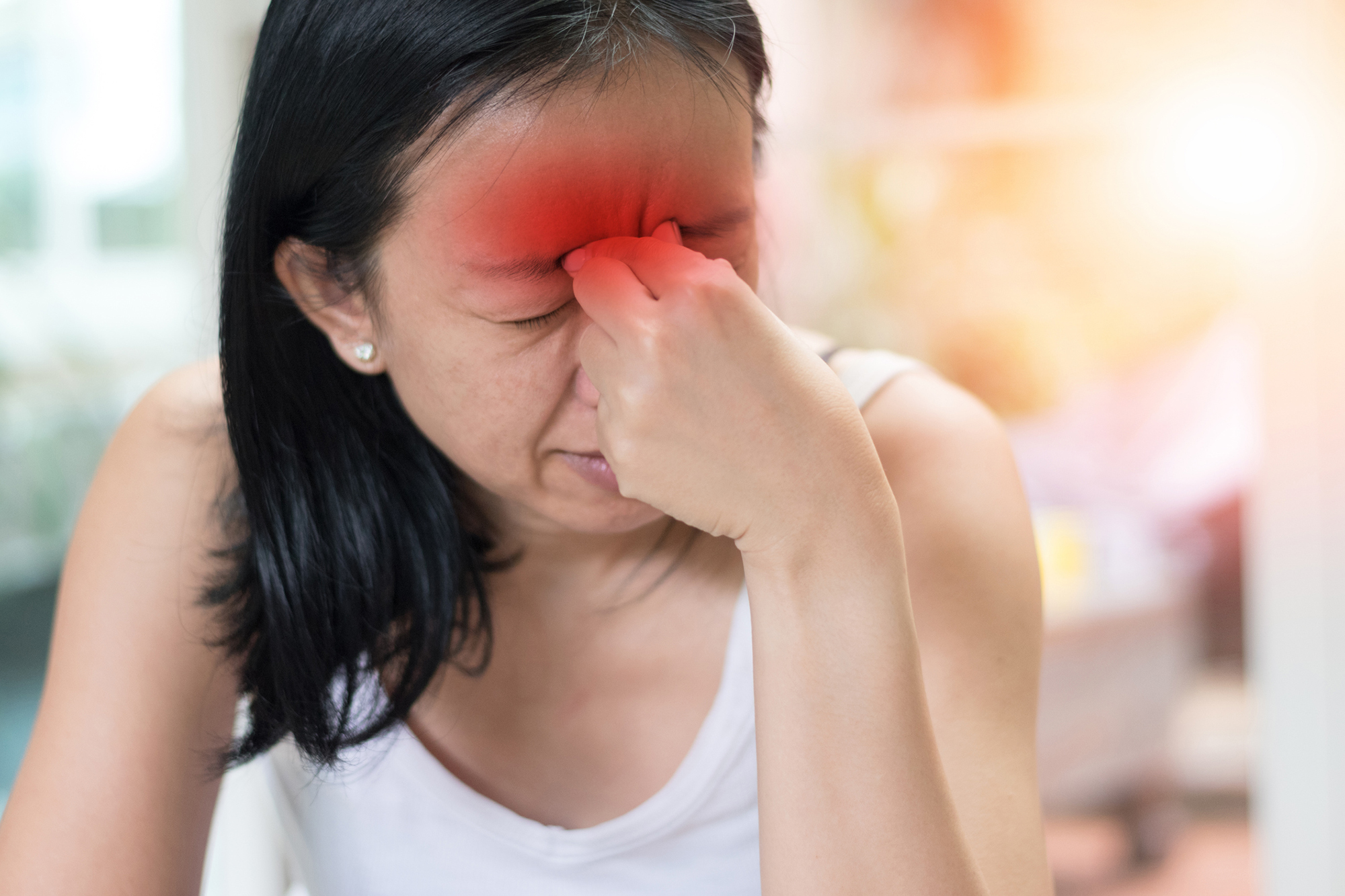 Person with sinusitis with a hand to their forehead.
