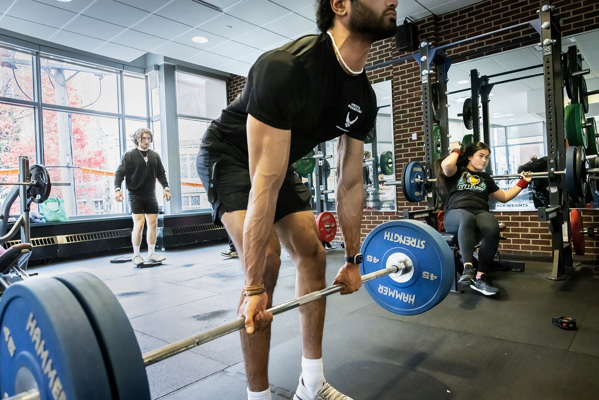 Christopher Spletzer (back left), a third-year mechanical engineering major in the School of Engineering and Applied Science, balances himself on a weight, while Davis prepares to do the bench press, and another student performs a deadlift. 