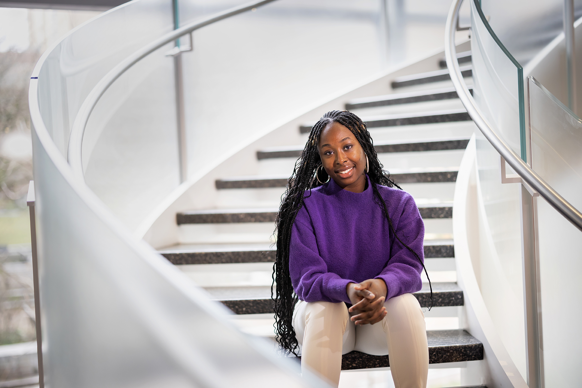 Taussia Boadi sits on the stairs inside the Wharton Academic Research building.