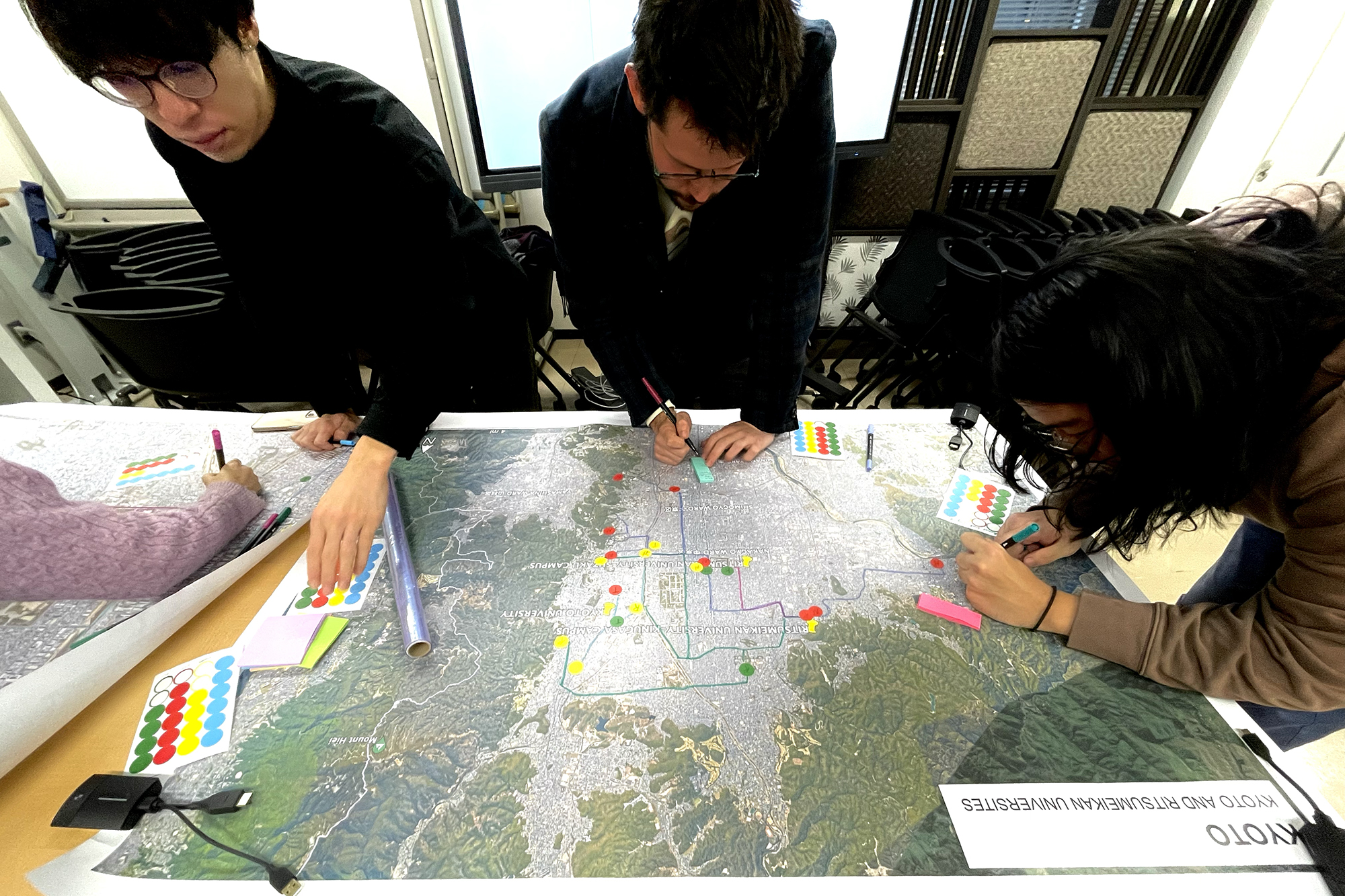 Three students work on a large map on a table.