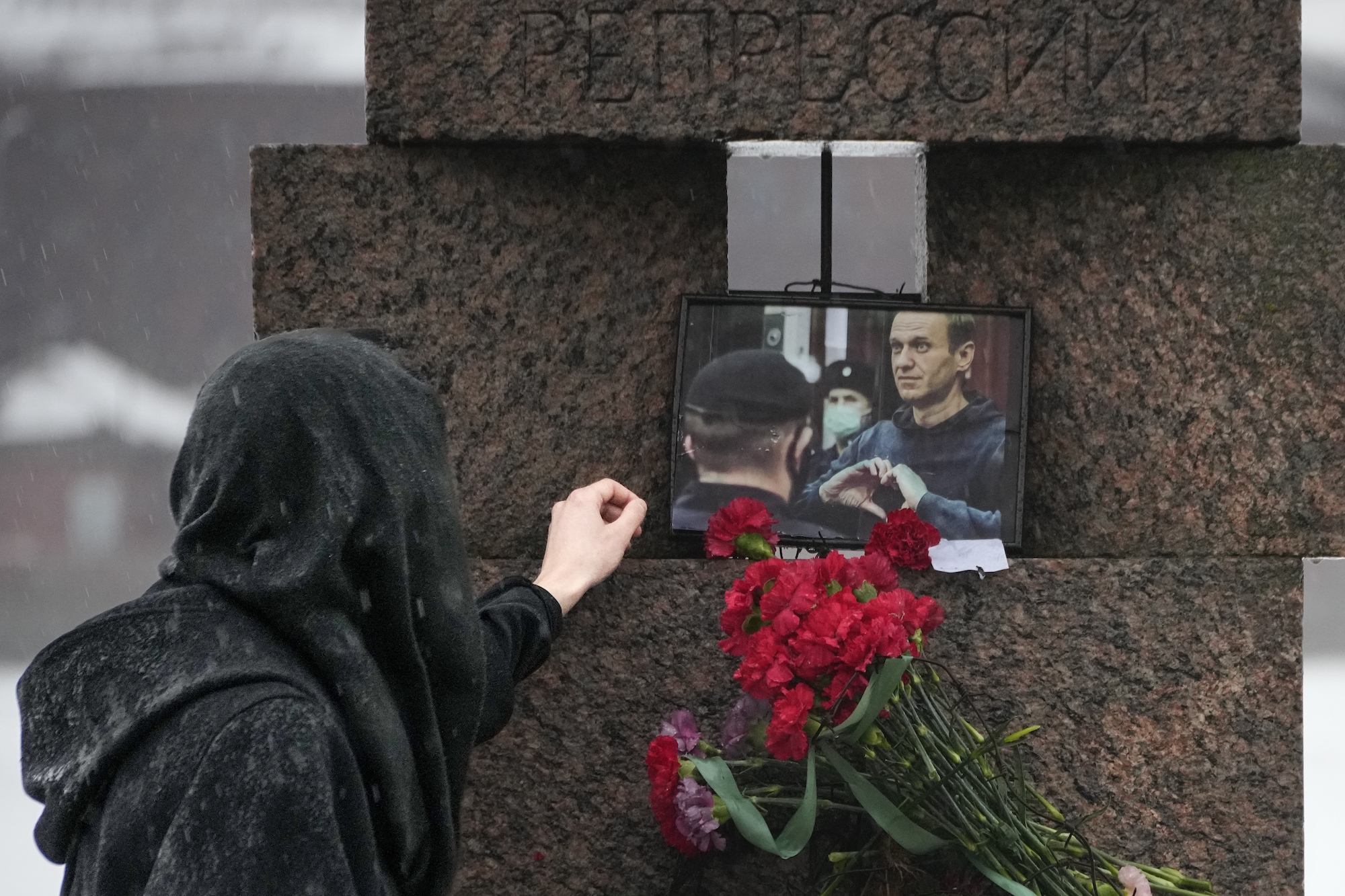 A person touches a photo of Alexei Navalny after laying flowers at the Memorial to Victims of Political Repression in St. Petersburg, Russia.