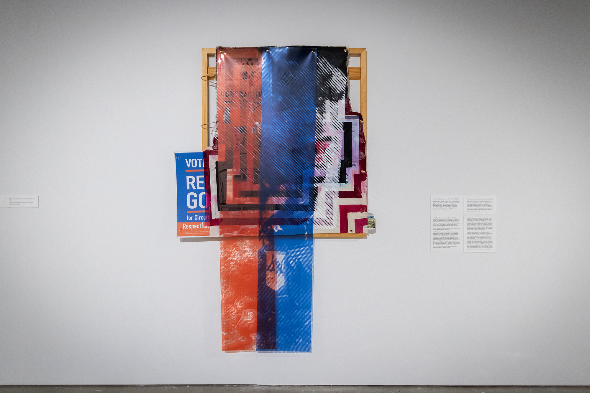 A painting exhibited with a vote sign peeking from behind several layers of material.