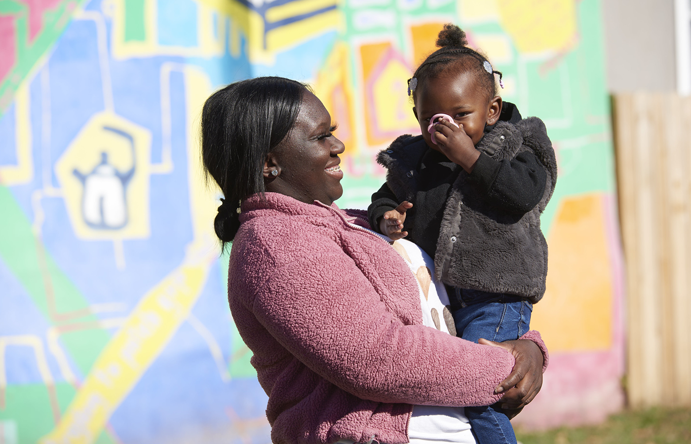 talicia with her daughter standing in front of a mural