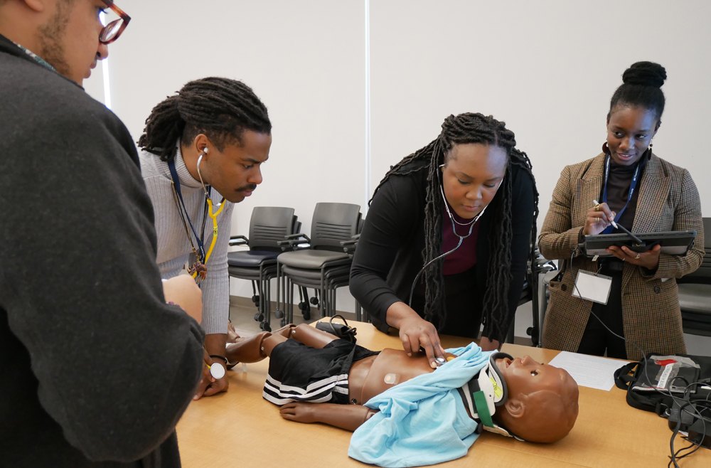 Claudia Gambrah-Lyles (right) facilitating medical simulations in heart and respiration monitoring for pediatric patients.