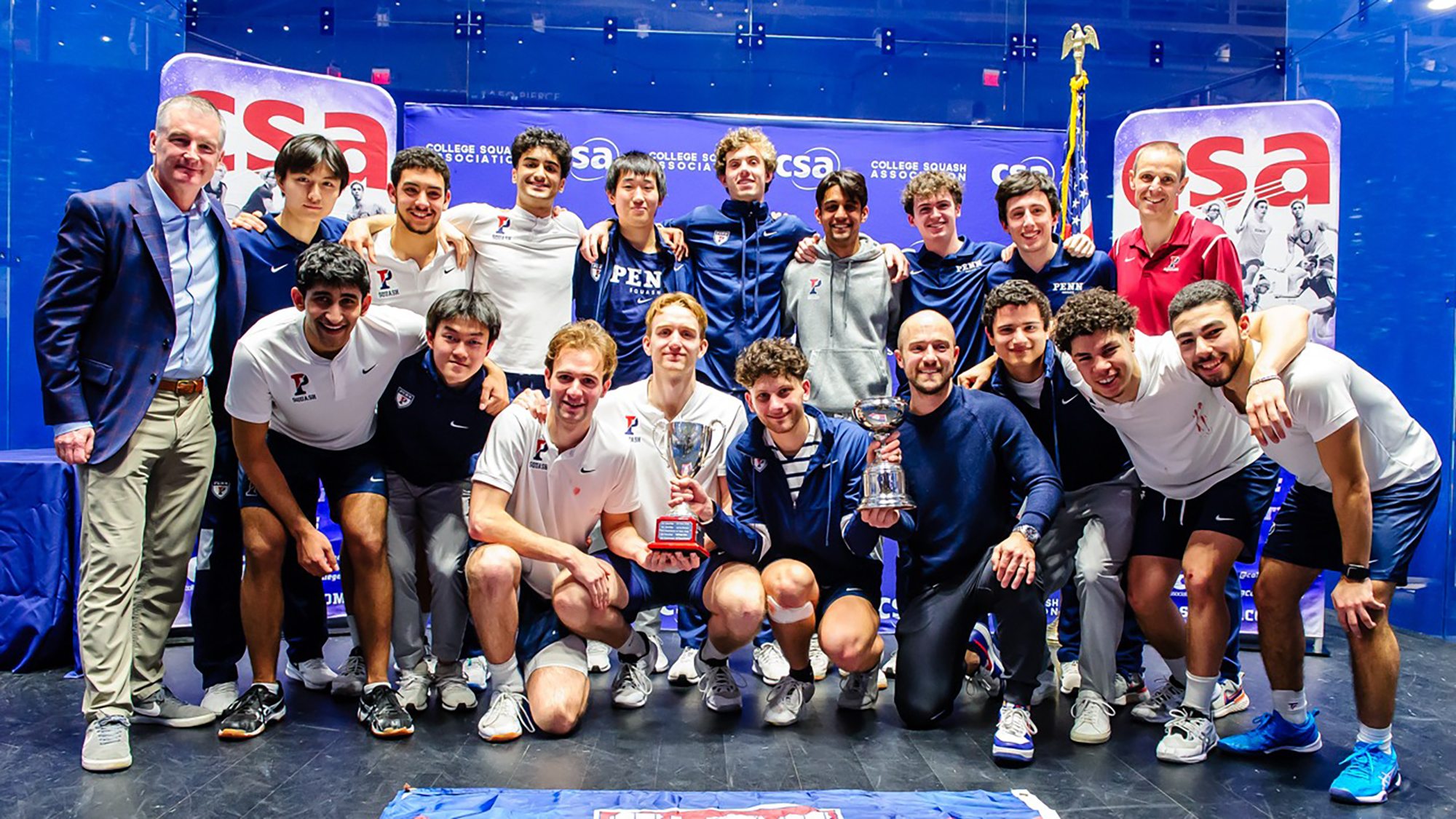 Members of the men's squash team pose with their championship trophy after defeating Trinity.
