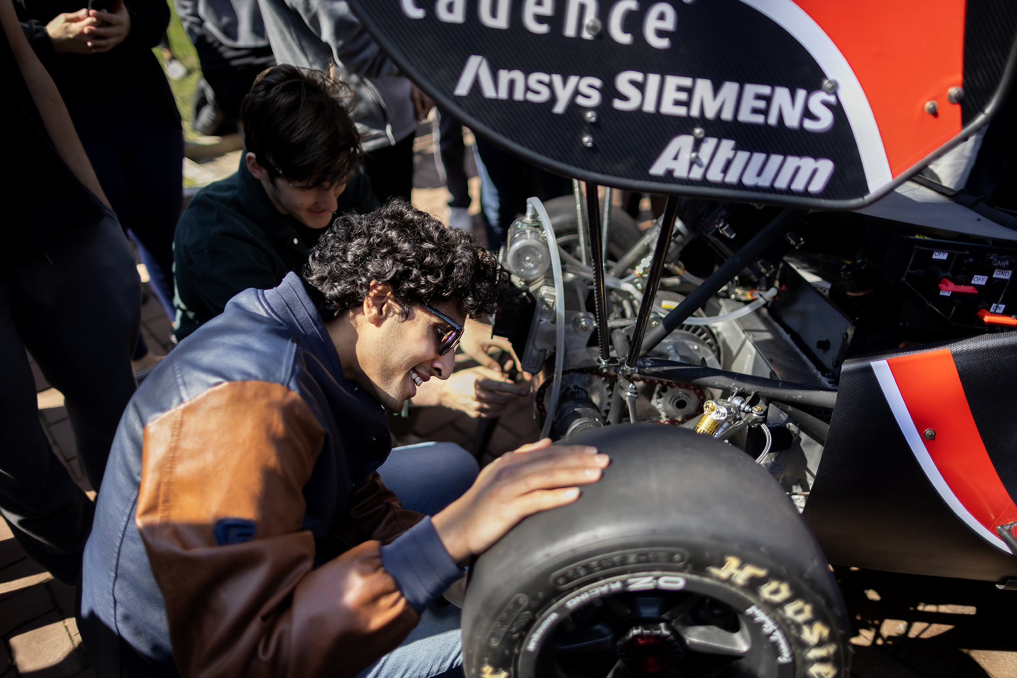 Student touches rear right wheel of an electric racecar.