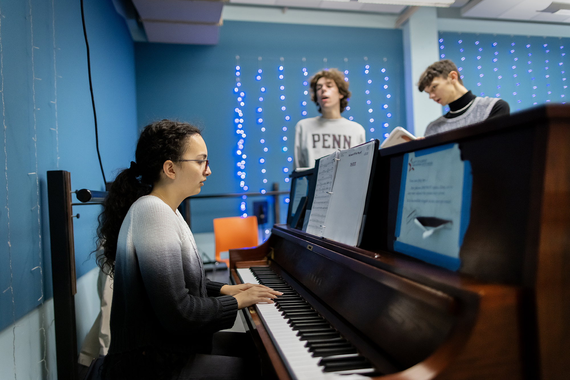 Members of a Penn musical group rehearsing to piano.
