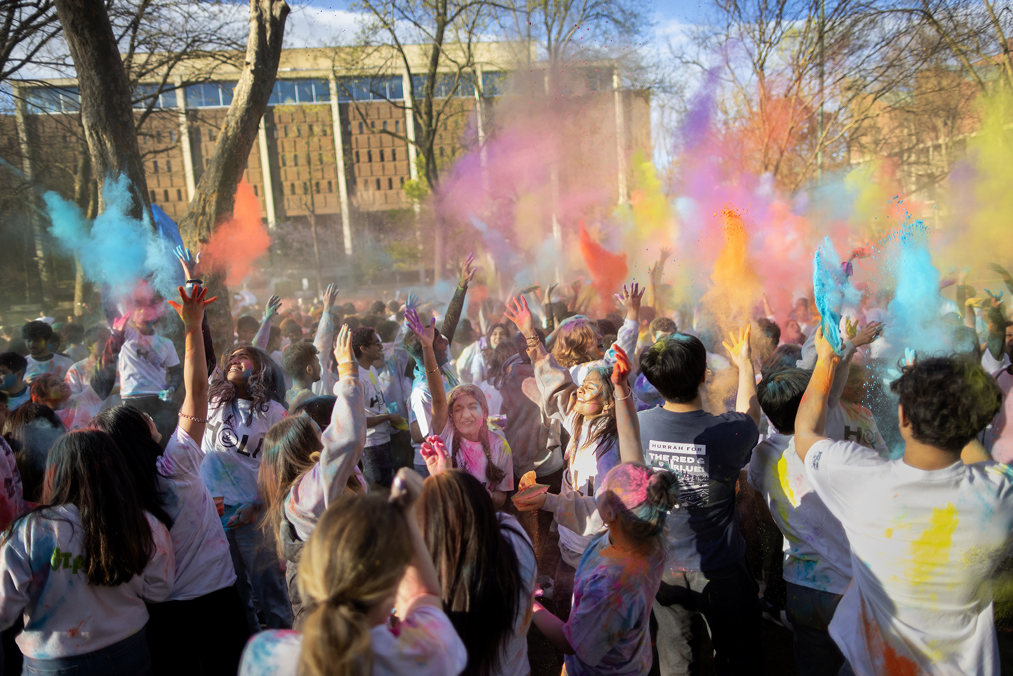 Penn students throw colored powder in the air on College Green while celebrating Holi.