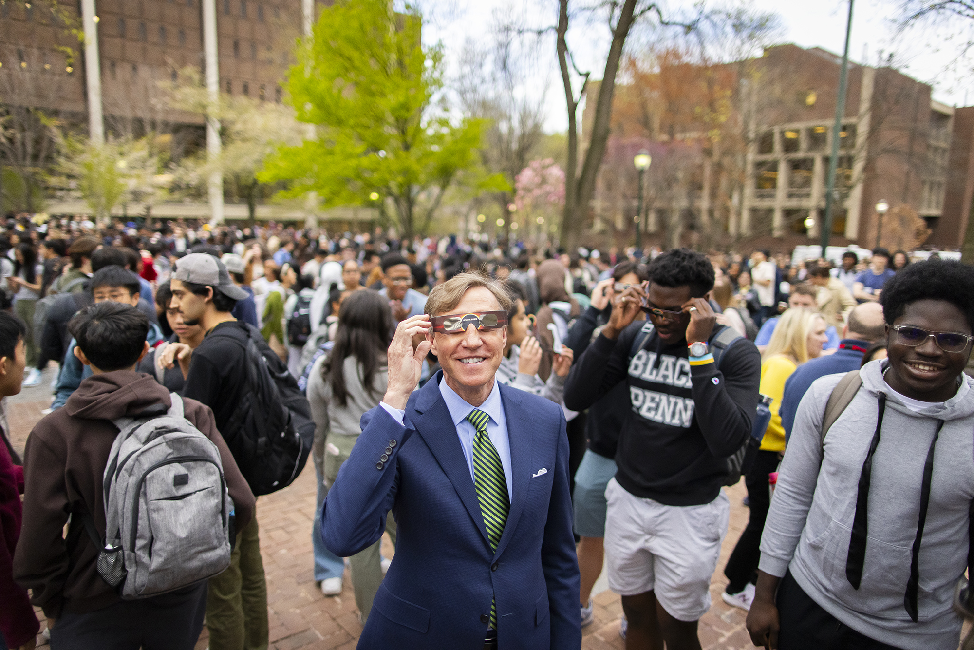 Penn’s president J. Larry Jameson on Locust Walk wearing eclipse glasses during the eclipse of 2024.