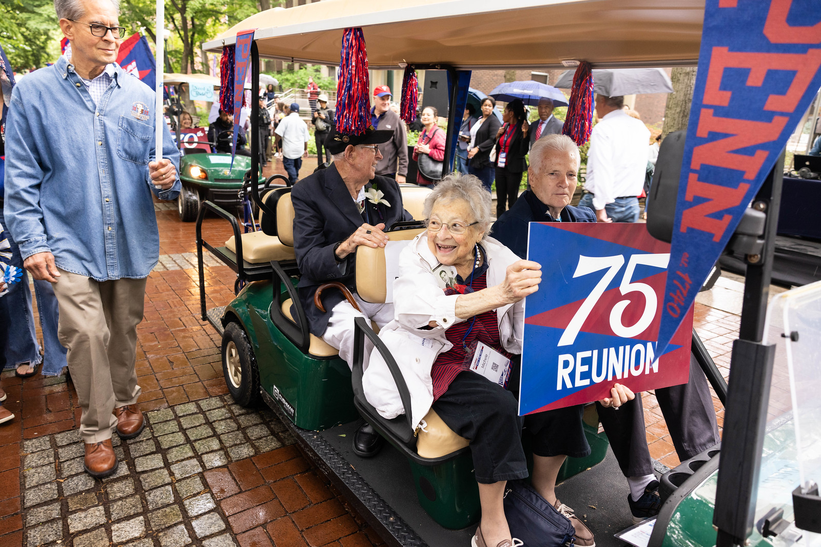Woman holding 75th Reunion Sign in golf cart at parade