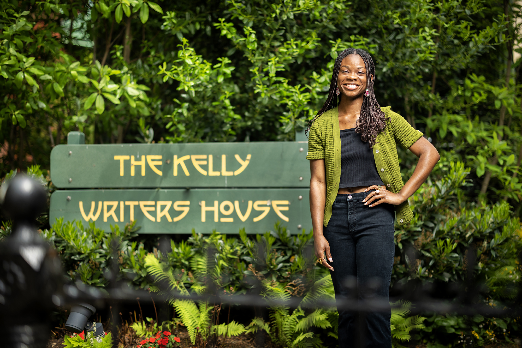 Deborah Olatunji stands next to a sign reading, "The Kelly Writers House"