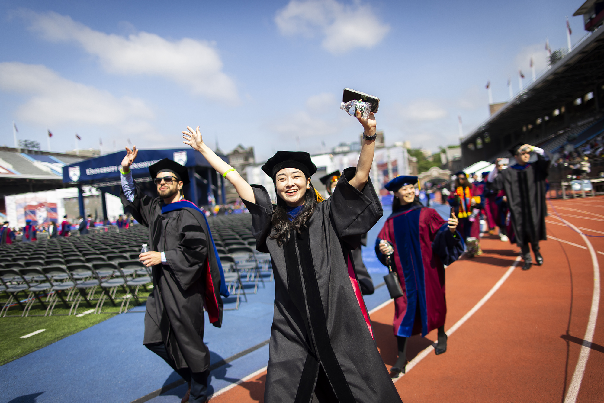 student waving as they enter franklin field during commencement