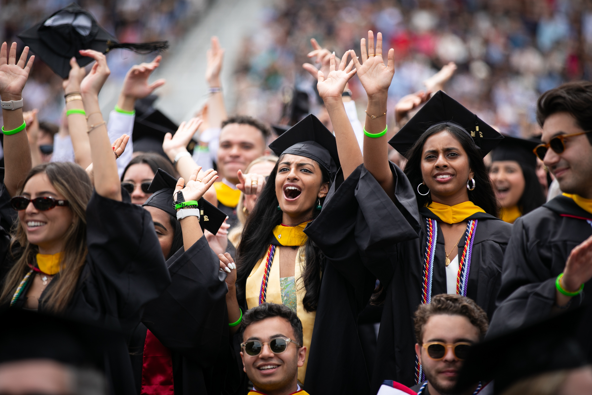 students cheer with arms raised during commencement