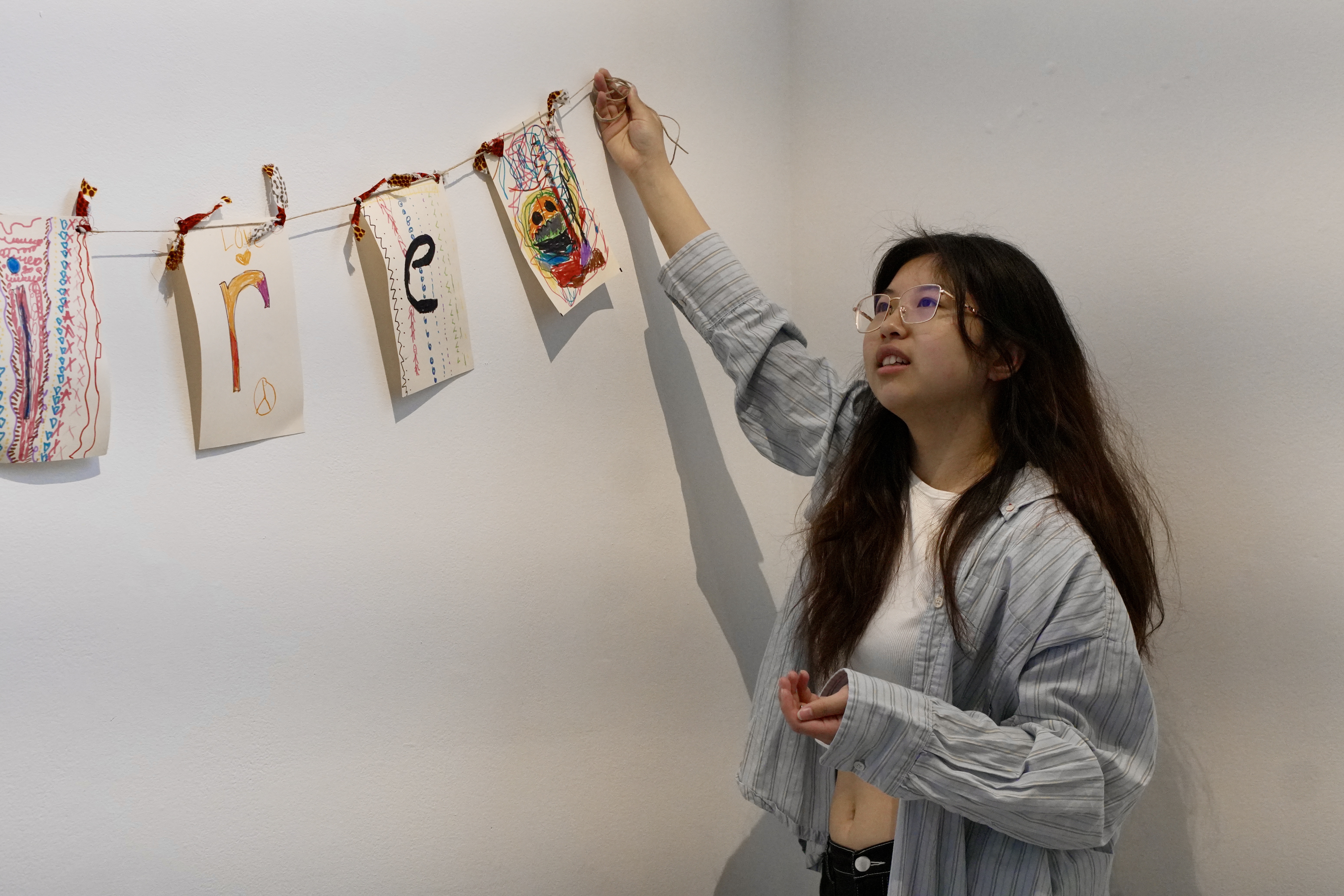 Natalie Cheng hanging paper artworks on a wall