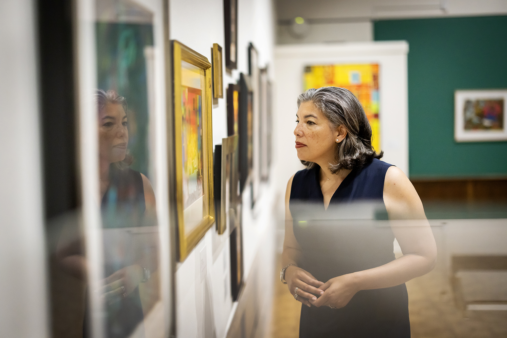 Gwendolyn DuBois Shaw looking at paintings on a wall in a gallery