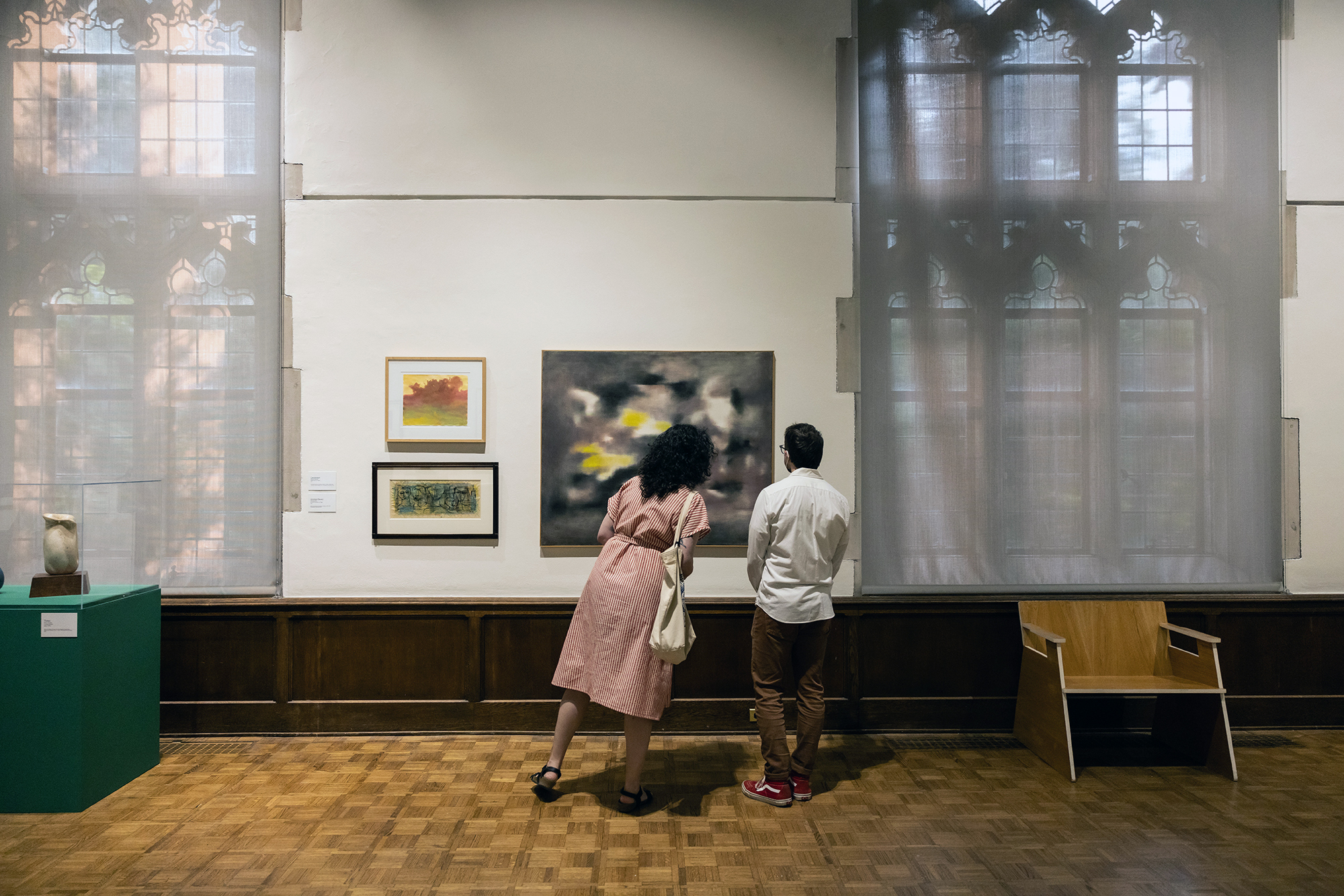 Two people look closely at a painting in the Arthur Ross Gallery.