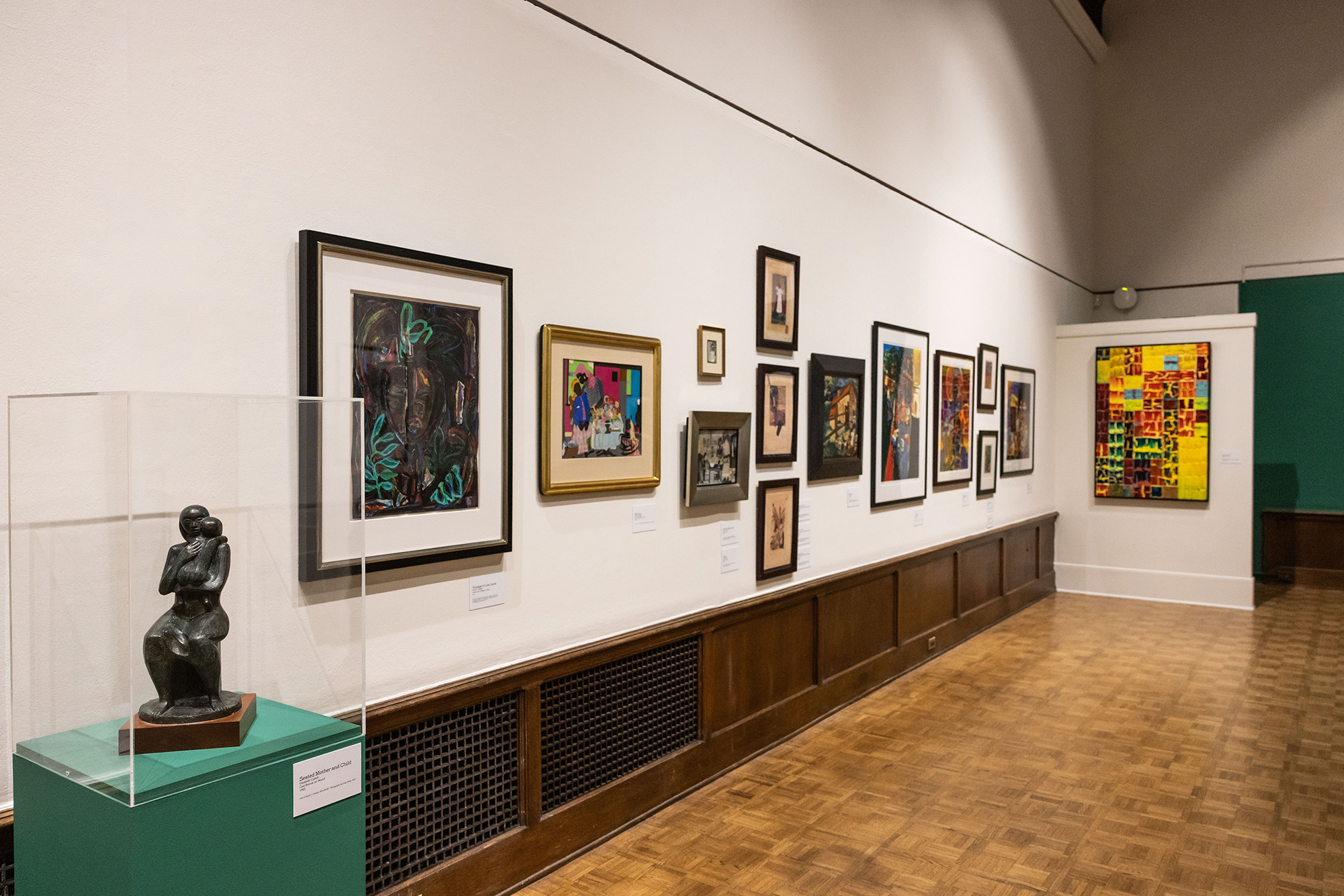 A wall of the Arthur Ross Gallery with David Driskell paintings and sculpture.