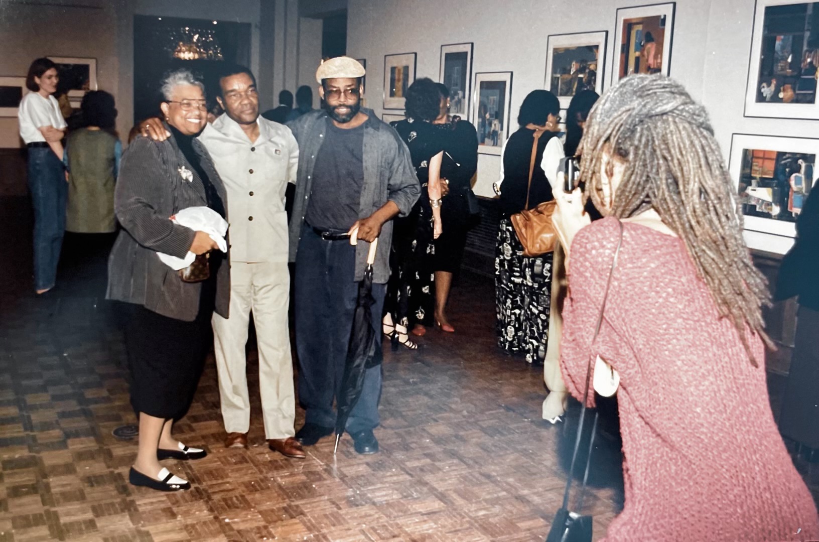 three people standing in an art gallery getting their photo taken