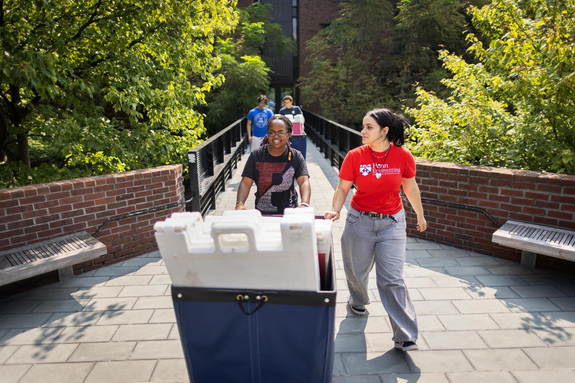 Nilla Orina pushes a Move-In cart with other Move-In coordinators on Penn’s campus.