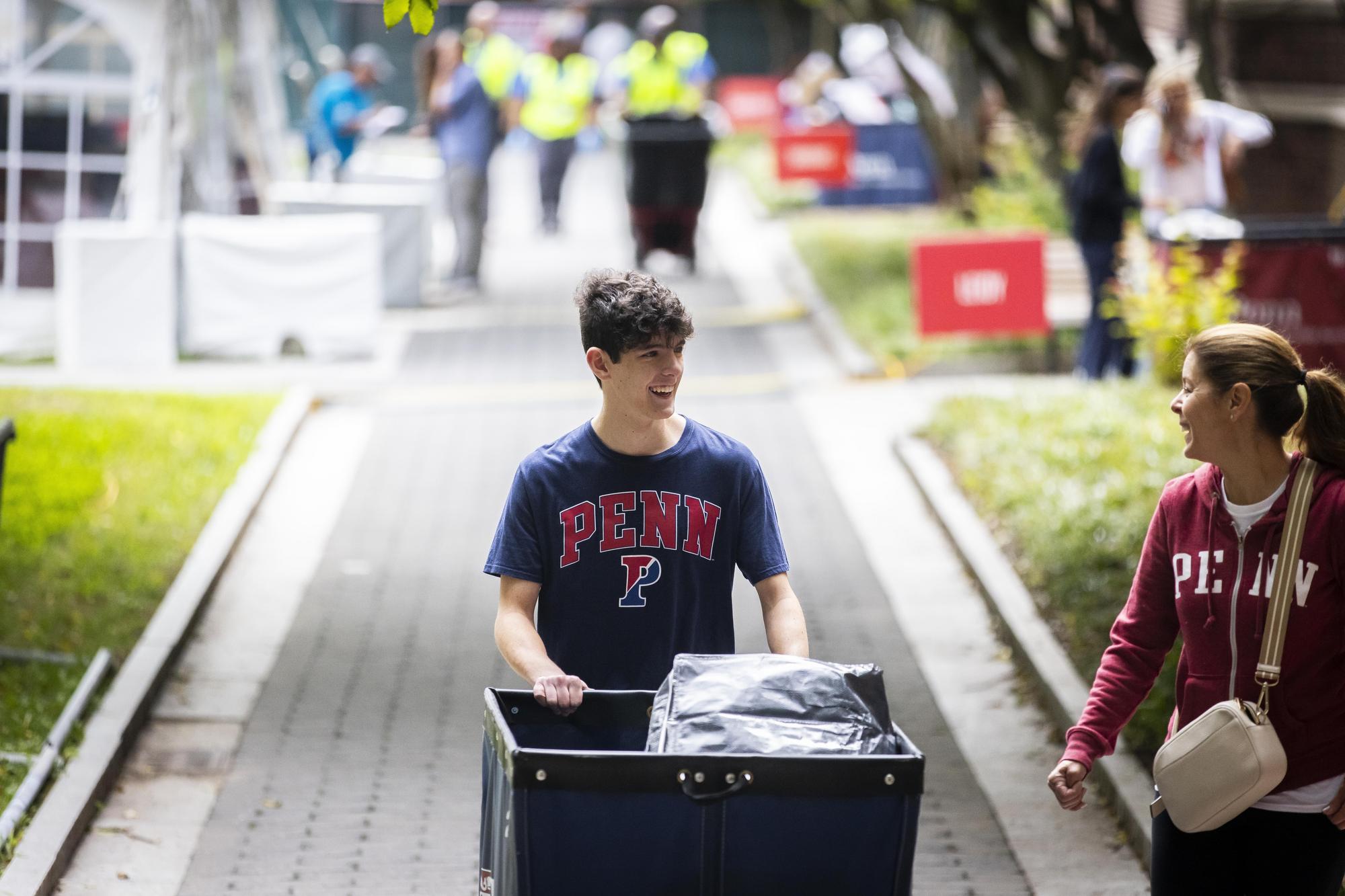 A Penn student and their parent pushing a Move-In cart on campus on Move-In day.